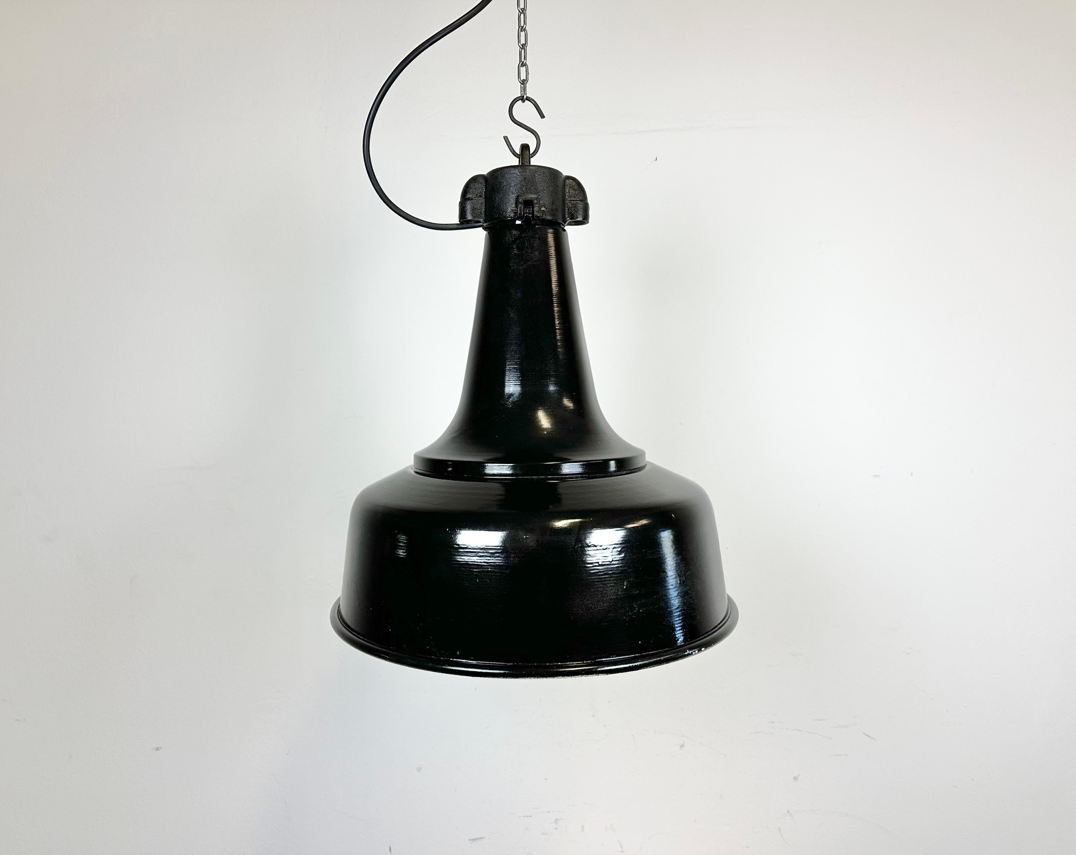 Industrial iron black painted pendant light made by in former Czechoslovakia during the 1970s. White inside the shade. Cast iron top. The porcelain socket requires standard E 27/ E26 light bulbs. New wire. Fully functional. The weight of the lamp is