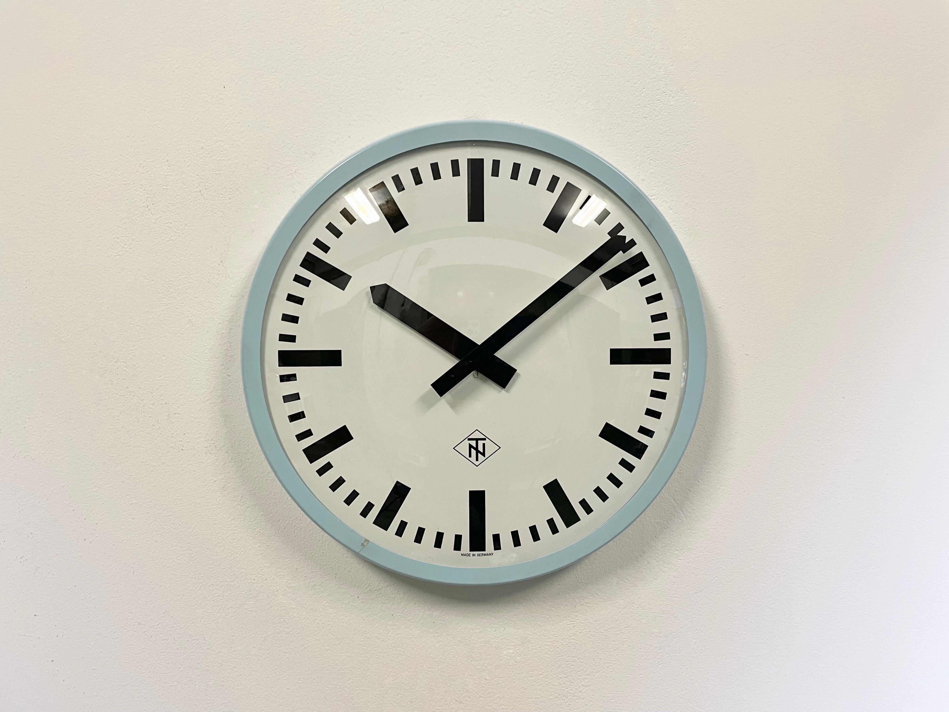 Wall clock produced by TN Telefonbau und Normalzeit in Germany during the 1960s. It features a blue bakelite frame, a white metal dial, an aluminium hands and a curved clear glass cover. The piece has been converted into a battery-powered clockwork