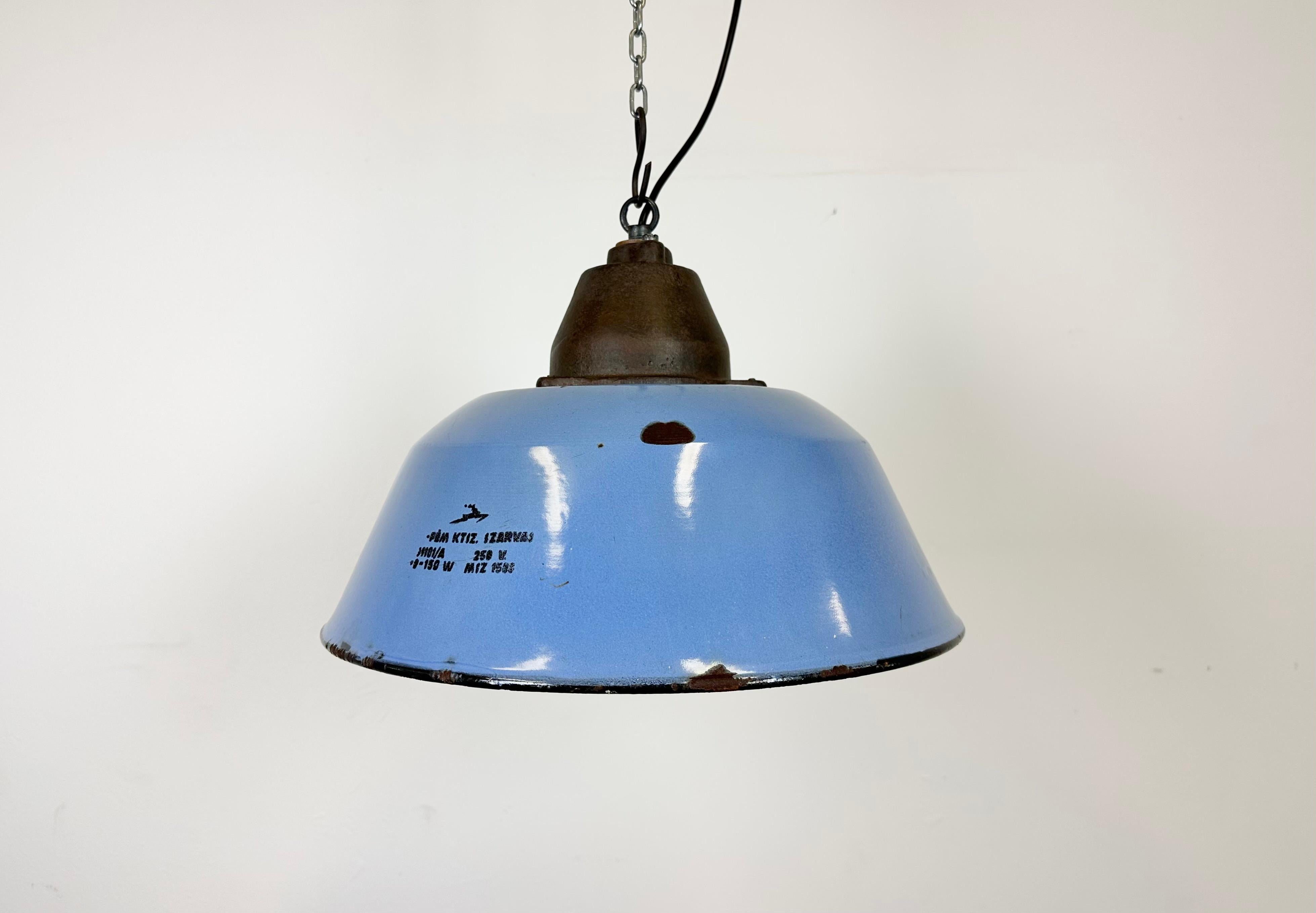 Industrial hanging lamp manufactured by Szarvasi Vas - Fém in Hungary during the 1960s. It features a blue enamel shade, white enamel interior and a cast iron top. New porcelain socket requires E 27/ E26 light bulbs. New wire. The diameter of the