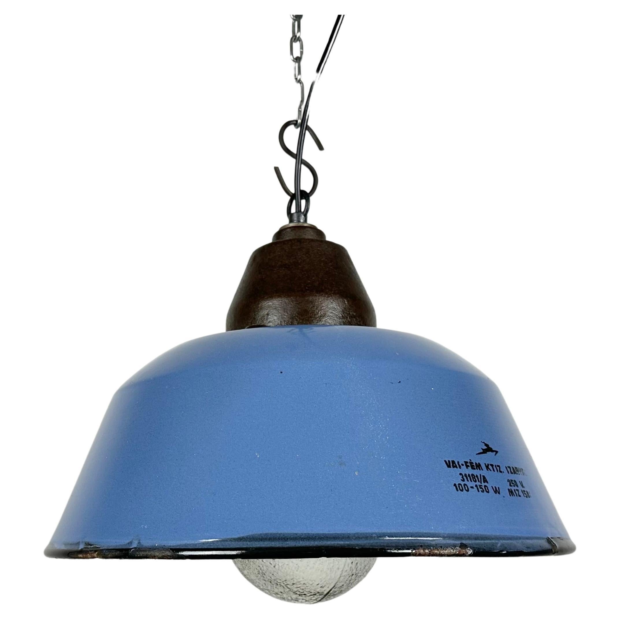 Industrial hanging lamp manufactured by Szarvasi Vas - Fém in Hungary during the 1960s. It features a blue enamel shade, a white enamel interior, a cast iron top and a frosted glass cover New porcelain socket requires E 27/ E26 light bulbs. New