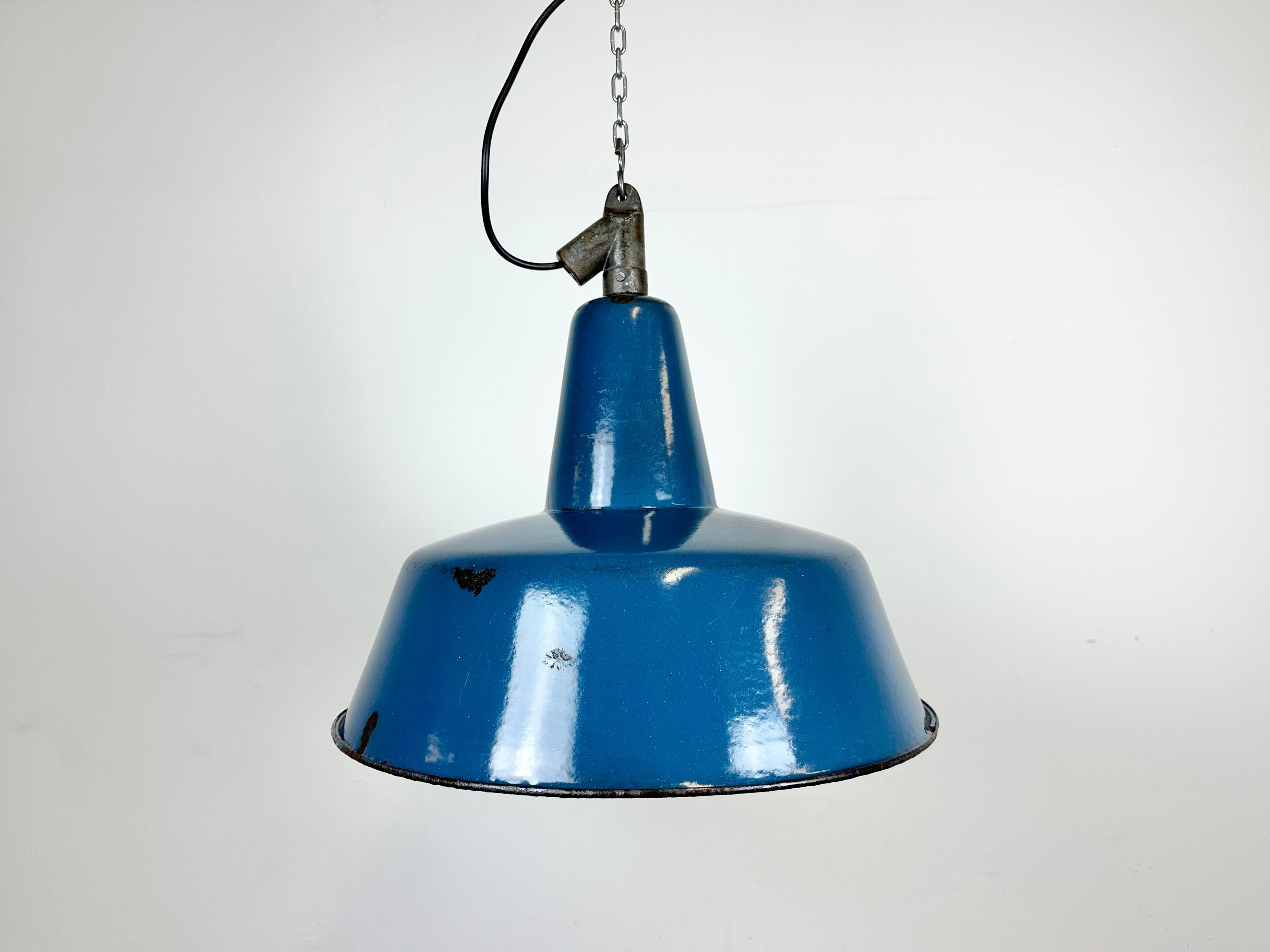 Industrial blue enamel pendant light made in Poland during the 1960s. White enamel inside the shade. Cast iron top. The porcelain socket requires E 27/ E 26 light bulbs. New wire. The weight of the lamp is 2,5 kg.