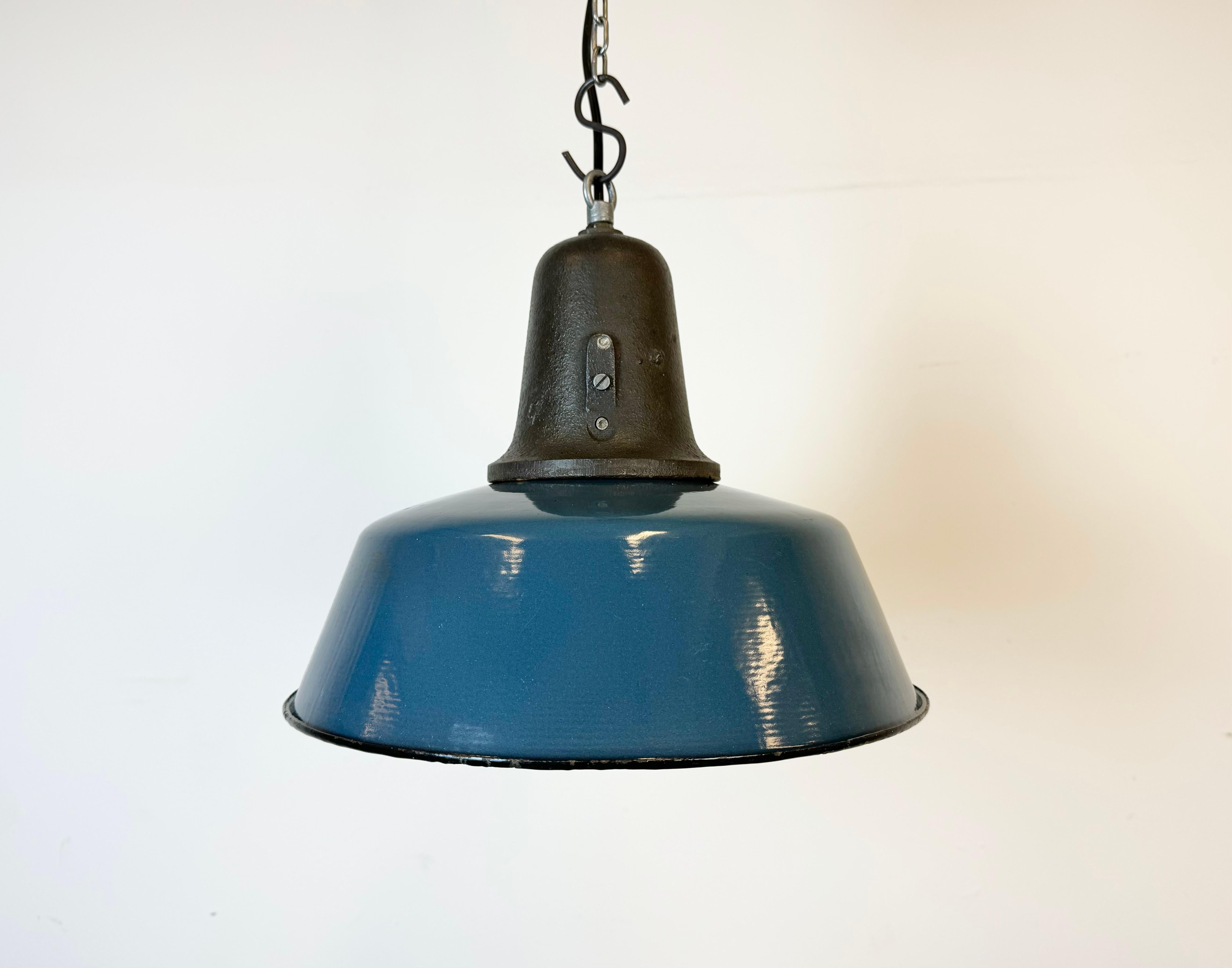 Lampe pendante industrielle en émail bleu fabriquée en Pologne dans les années 1960. Émail blanc à l'intérieur de la teinte. Dessus en fonte. La douille en porcelaine est compatible avec les ampoules standard E 27/ E 26. Un nouveau fil. Le poids de