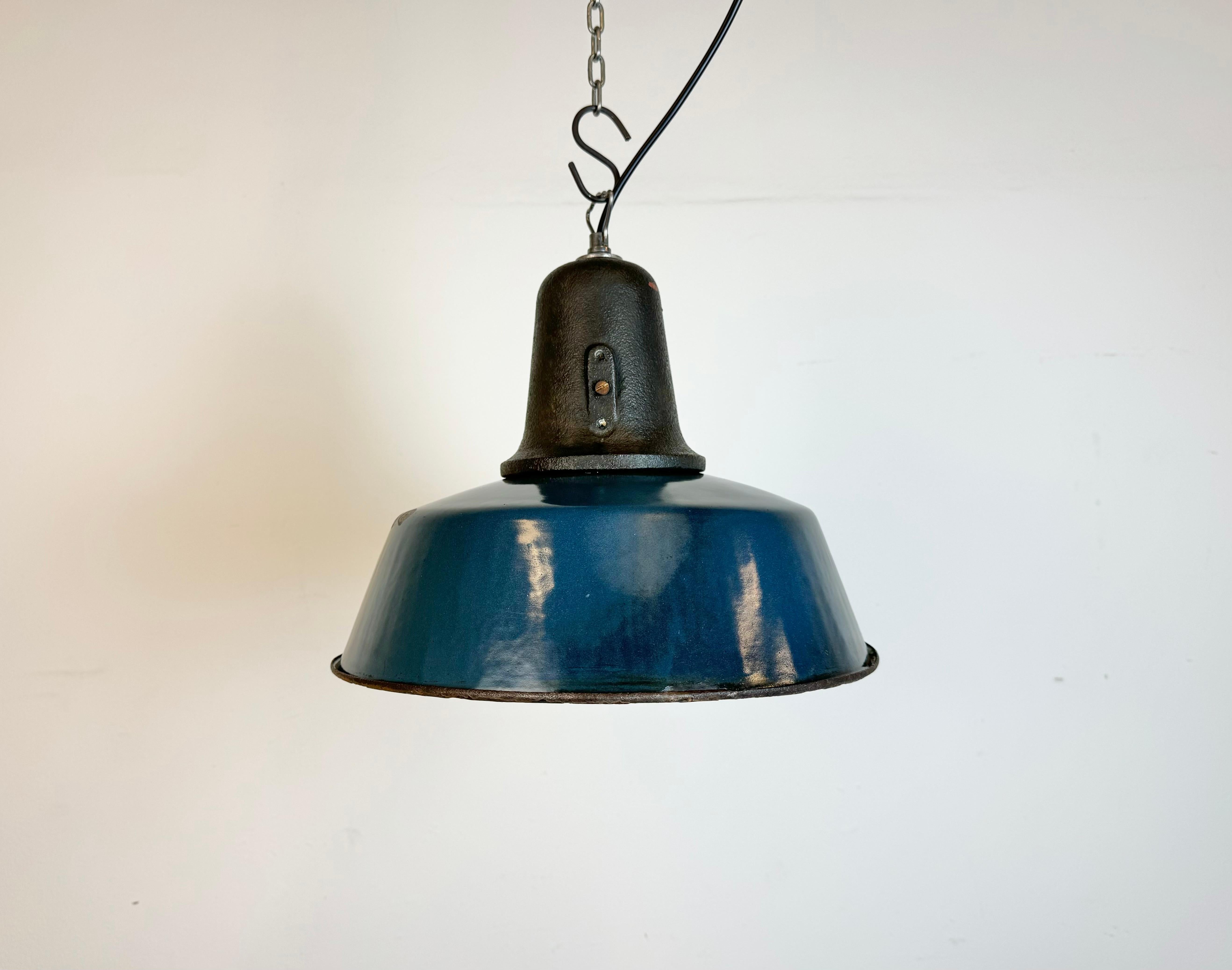 Industrial blue enamel pendant light made in Poland during the 1960s. White enamel inside the shade. Cast iron top. The porcelain socket requires standard E 27/ E 26 light bulbs. New wire. The weight of the lamp is 2,3 kg. The diameter of the shade