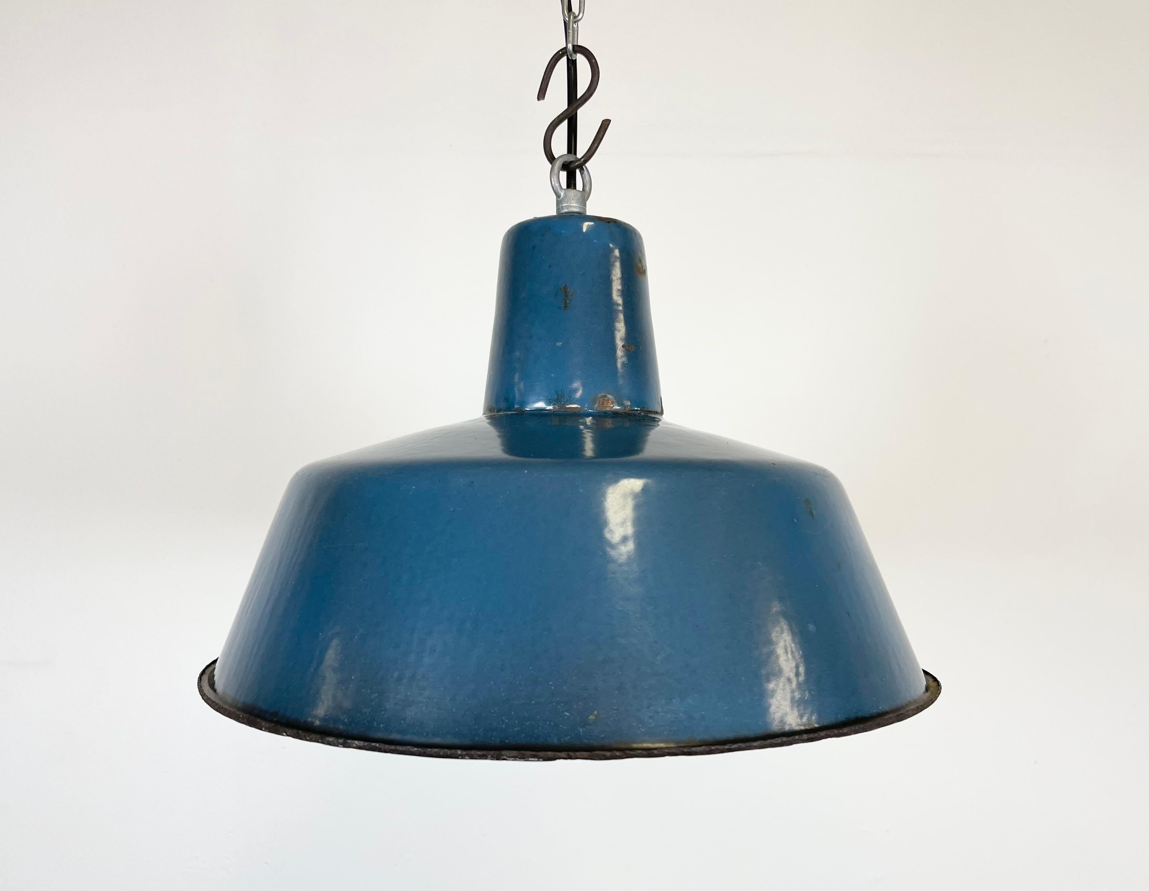 Industrial blue enamel pendant light made in Poland during the 1960s. White enamel inside the shade. Iron top. The bakelite socket requires E 27 light bulbs. New wire. Fully functional. The weight of the lamp is 1,2 kg.