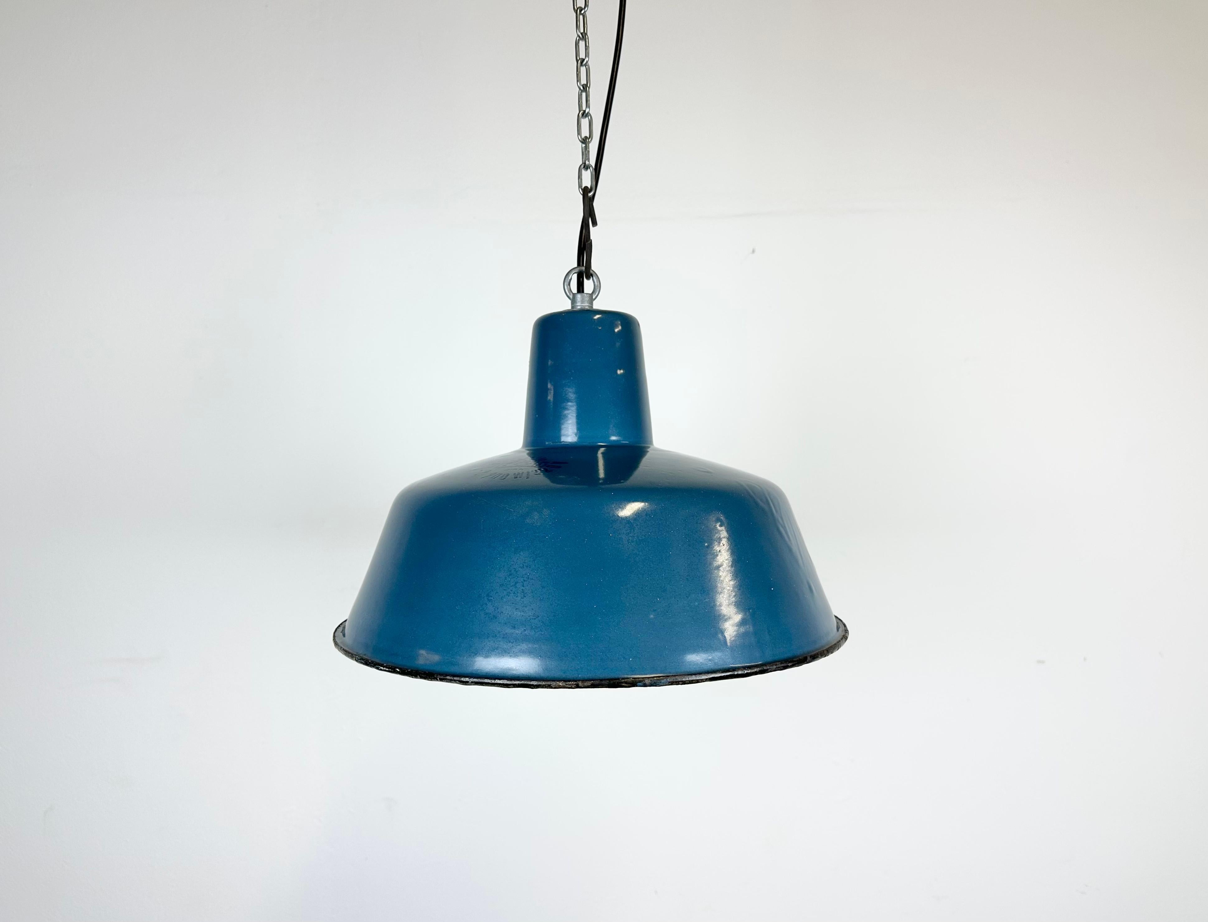 Industrial blue enamel pendant light made in Poland during the 1960s. White enamel inside the shade. Iron top. The porcelain socket requires E 27/ E 26 light bulbs. New wire. Fully functional. The weight of the lamp is 1,2 kg.