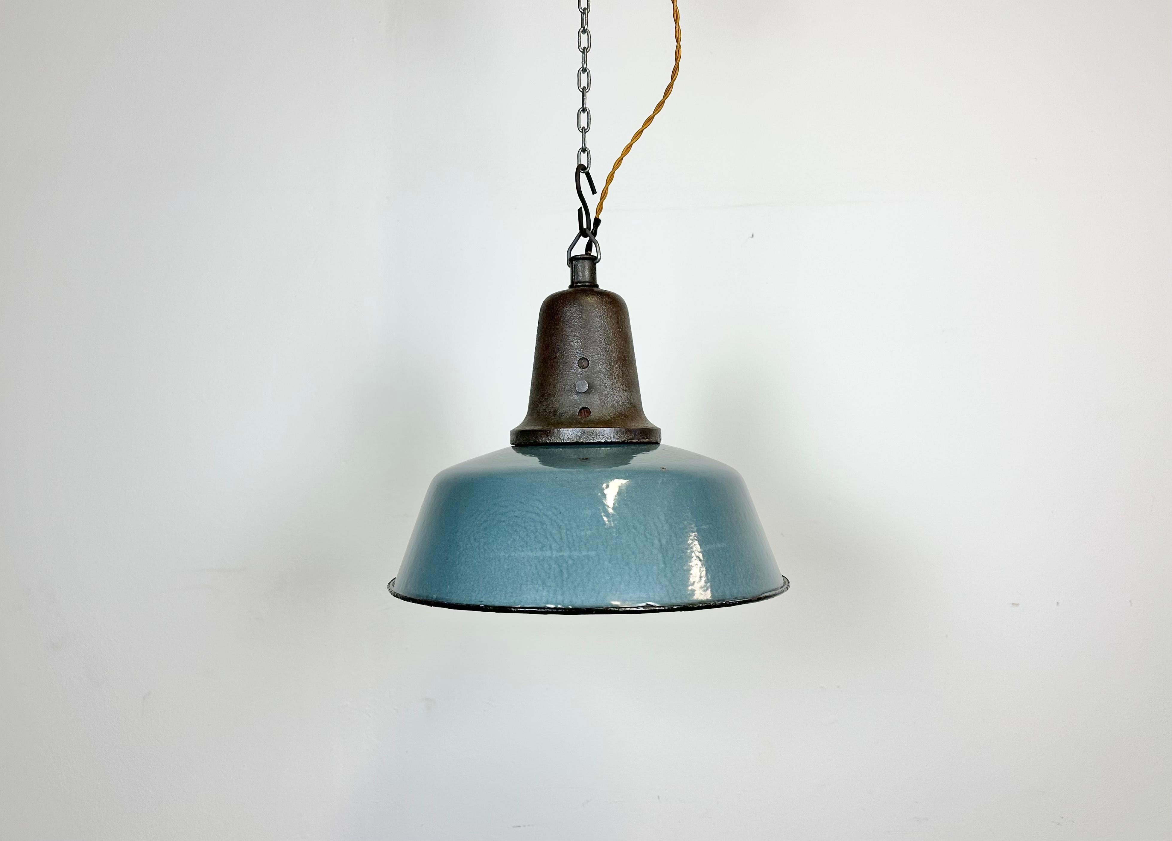 Industrial blue enamel pendant light made in Poland during the 1960s. White enamel inside the shade. Cast iron top. The porcelain socket requires E 27/ E26 light bulbs. New wire. Fully functional. The weight of the lamp is 2.8 kg.