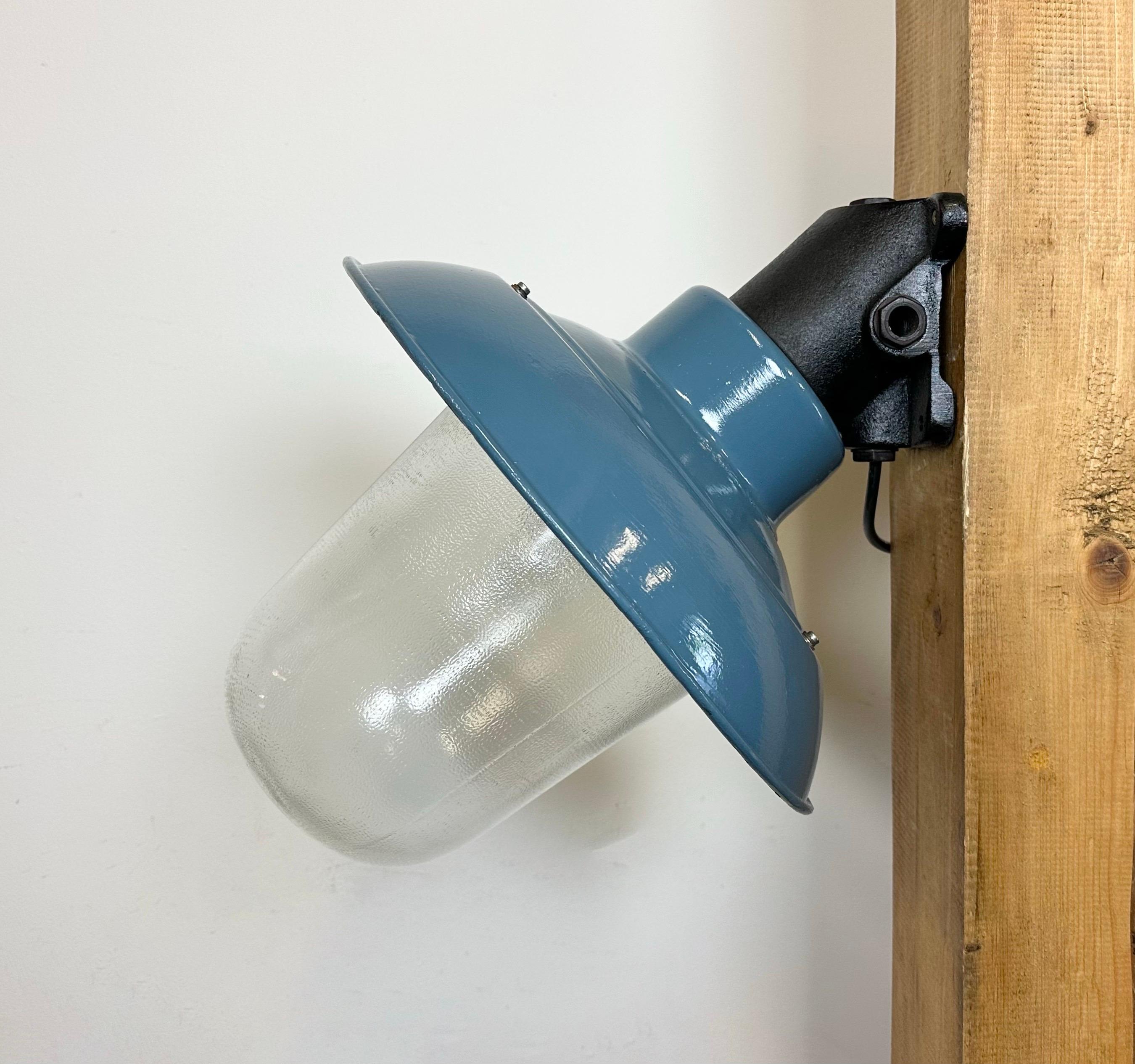 This Industrial wall lamp was designed in the 1960s and produced by Elektrosvit in the former Czechoslovakia. It features a cast iron wall mounting, a newly blue painted shade with a white enamel interior and a frosted glass cover. New porcelain
