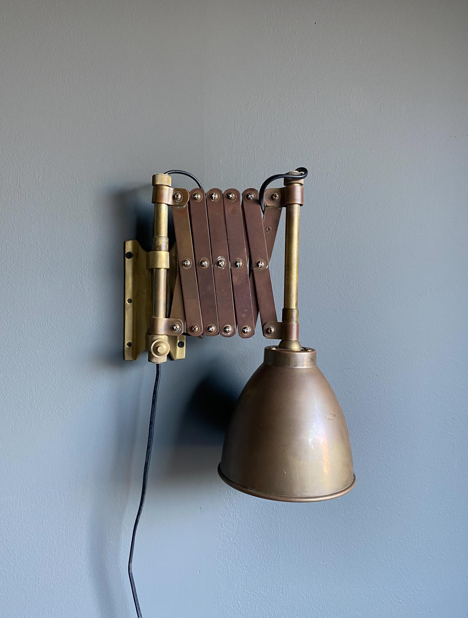 Industrial brass scissor wall lamp, 1950's. Beautiful original patina to the brass. This lamp extends from 11