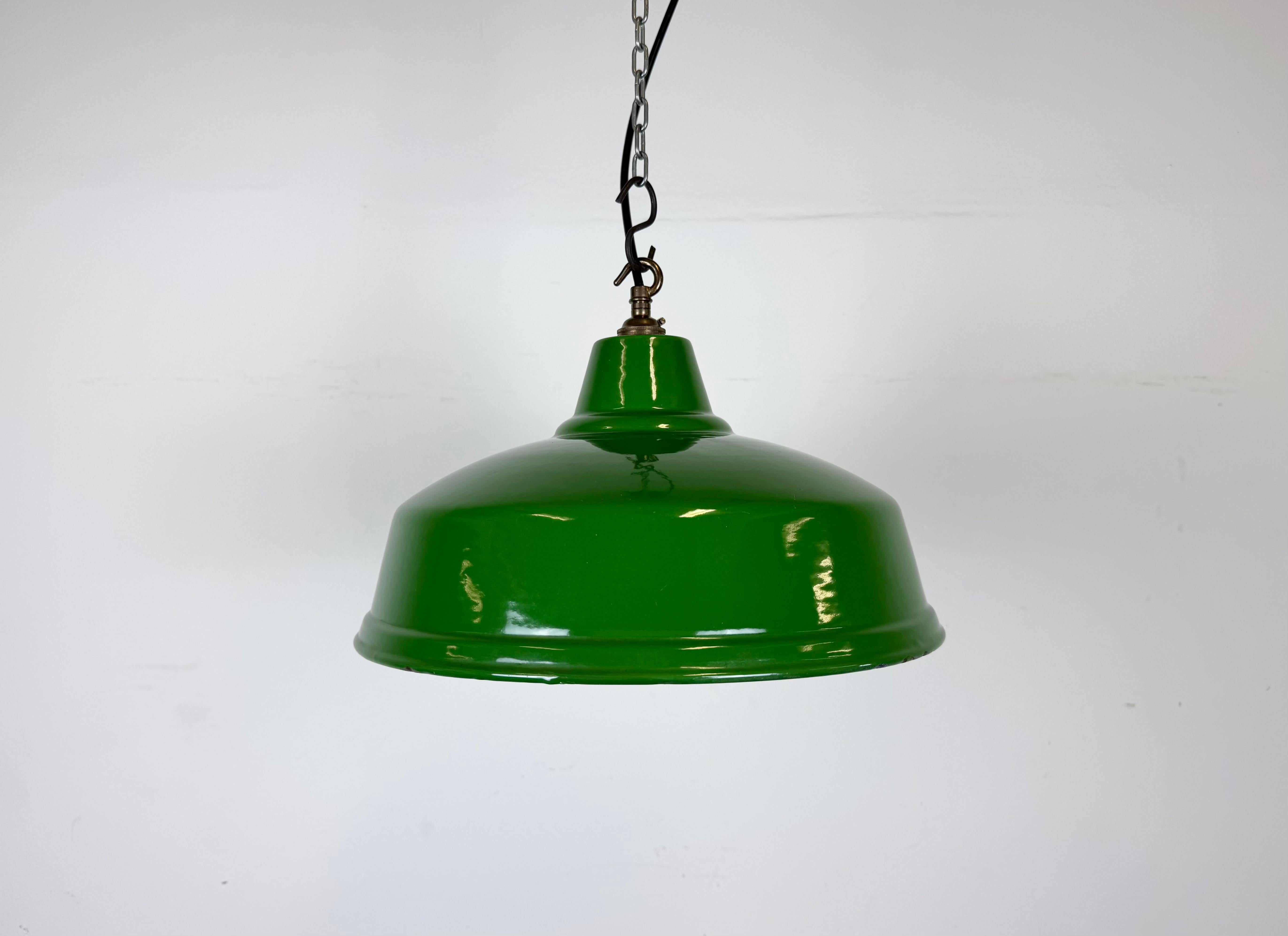 Lampada a sospensione industriale in smalto verde realizzata nel Regno Unito negli anni Sessanta. Smalto bianco all'interno del paralume. Top in ottone. L'attacco richiede lampadine a baionetta B22. Un nuovo cavo. Il peso della lampada è di 1,3 kg.