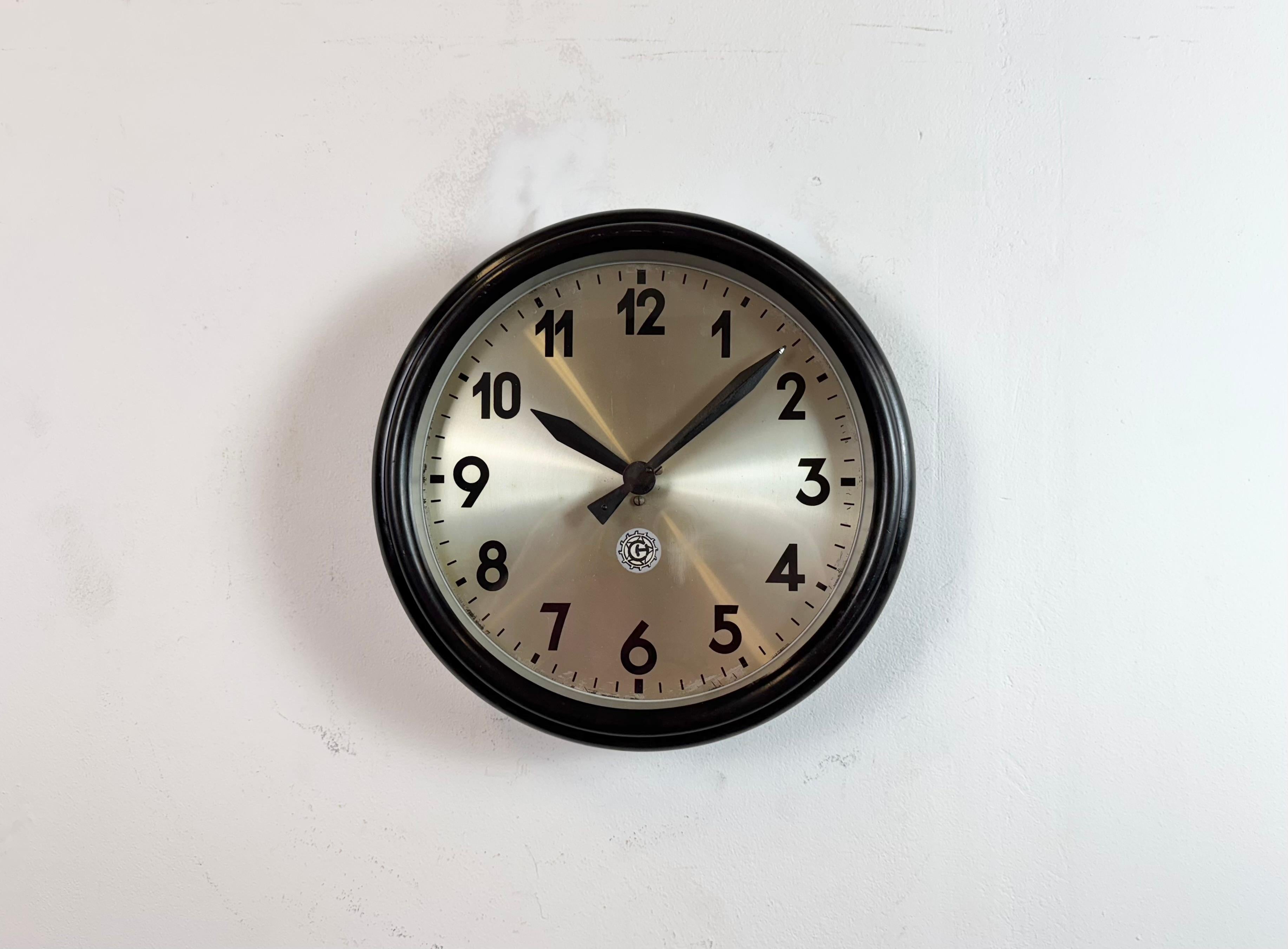 Este reloj de pared fue fabricado por Chronotechna en la antigua Checoslovaquia durante la década de 1950. Presenta un marco de baquelita marrón, una esfera de hierro y una tapa de cristal transparente. La pieza se ha convertido en un mecanismo de