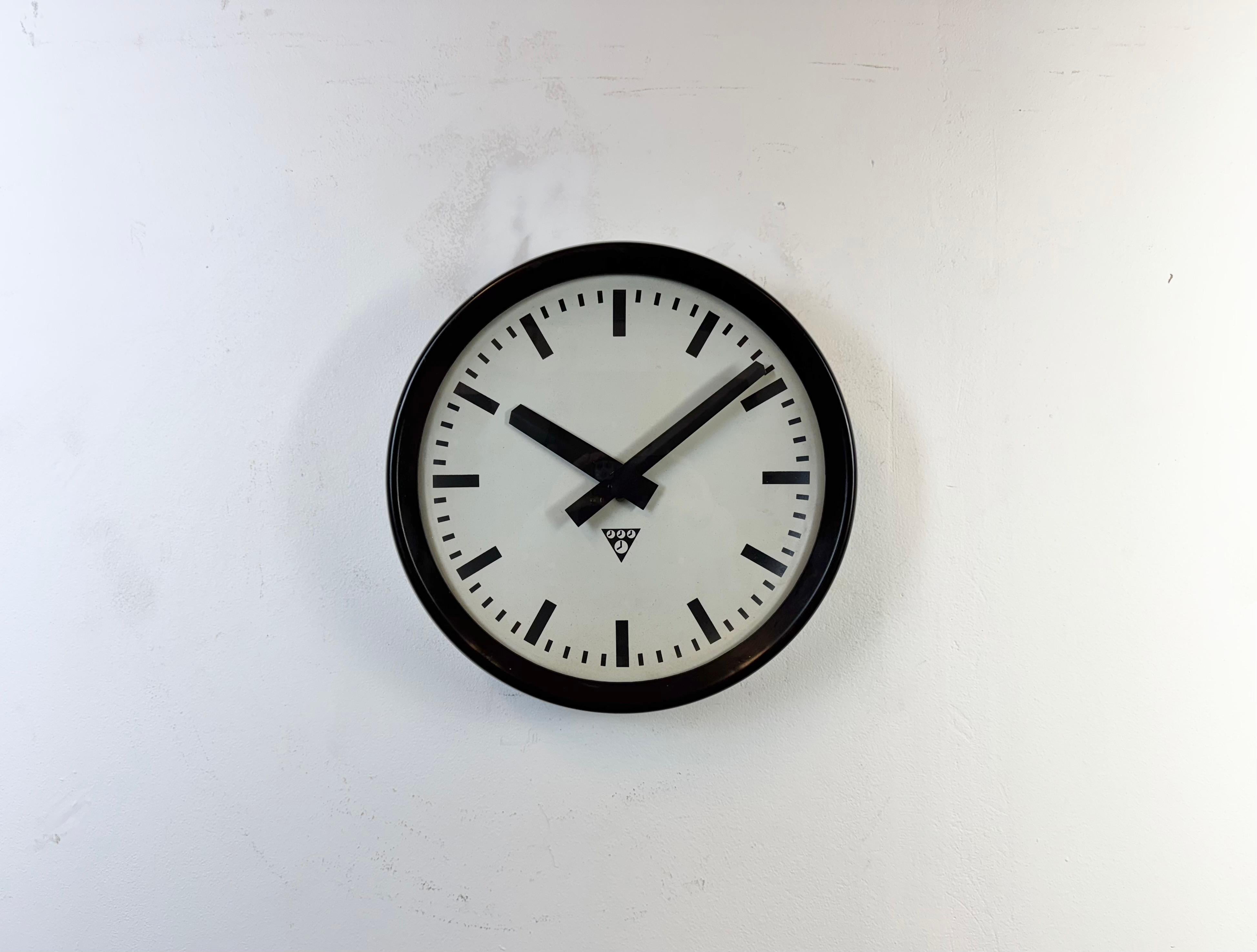 This wall clock was produced by Pragotron in former Czechoslovakia during the 1960s. It features a brown bakelite frame, an aluminium dial,hands and a convex clear glass cover. The piece has been converted into a battery-powered clockwork and