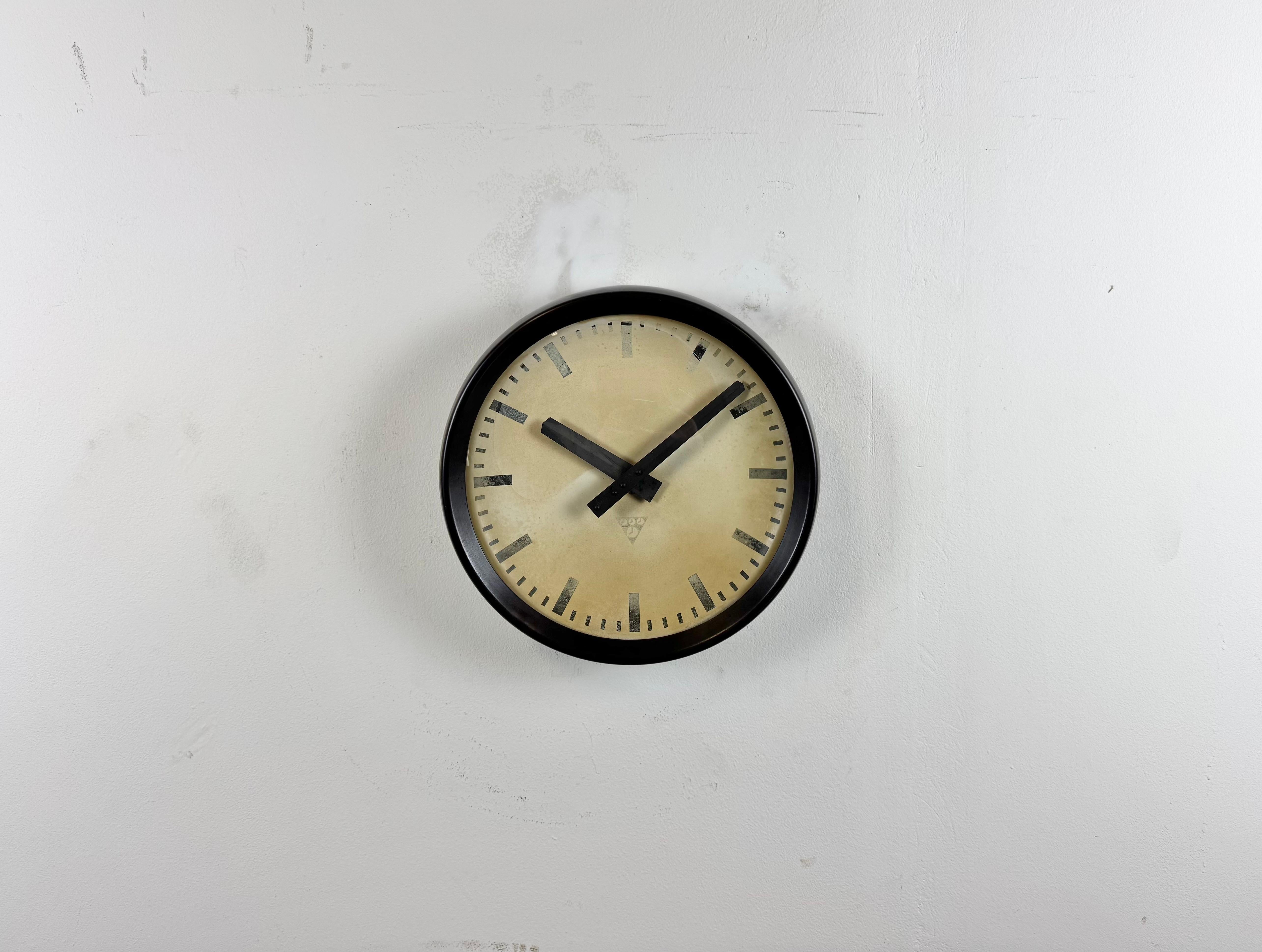 Este reloj de pared fue fabricado por Pragotron en la antigua Checoslovaquia durante la década de 1960. Presenta un marco de baquelita marrón, una esfera de aluminio, manecillas y una tapa de cristal transparente convexo. La pieza se ha convertido