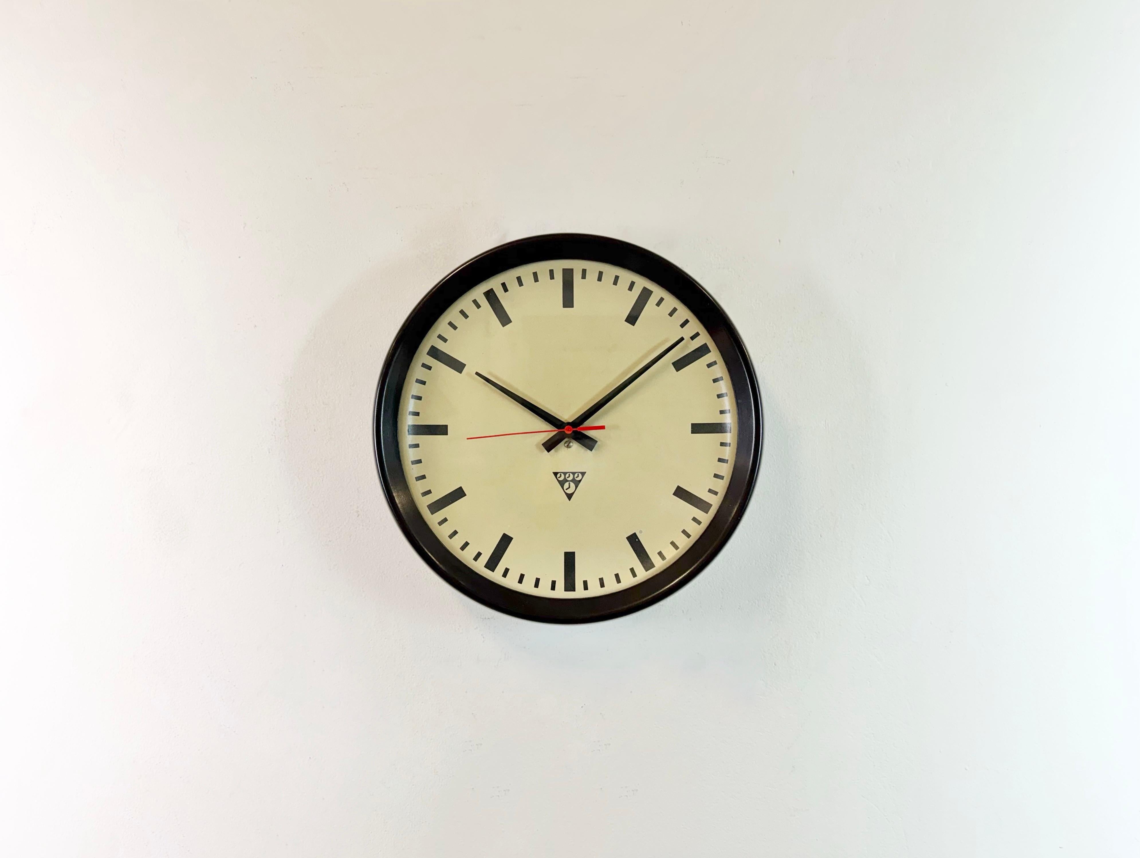 This wall clock was produced by Pragotron in former Czechoslovakia during the 1960s. It features a brown bakelite frame, an aluminium dial,hands and a clear glass cover. The piece has been converted into a battery-powered clockwork and requires only