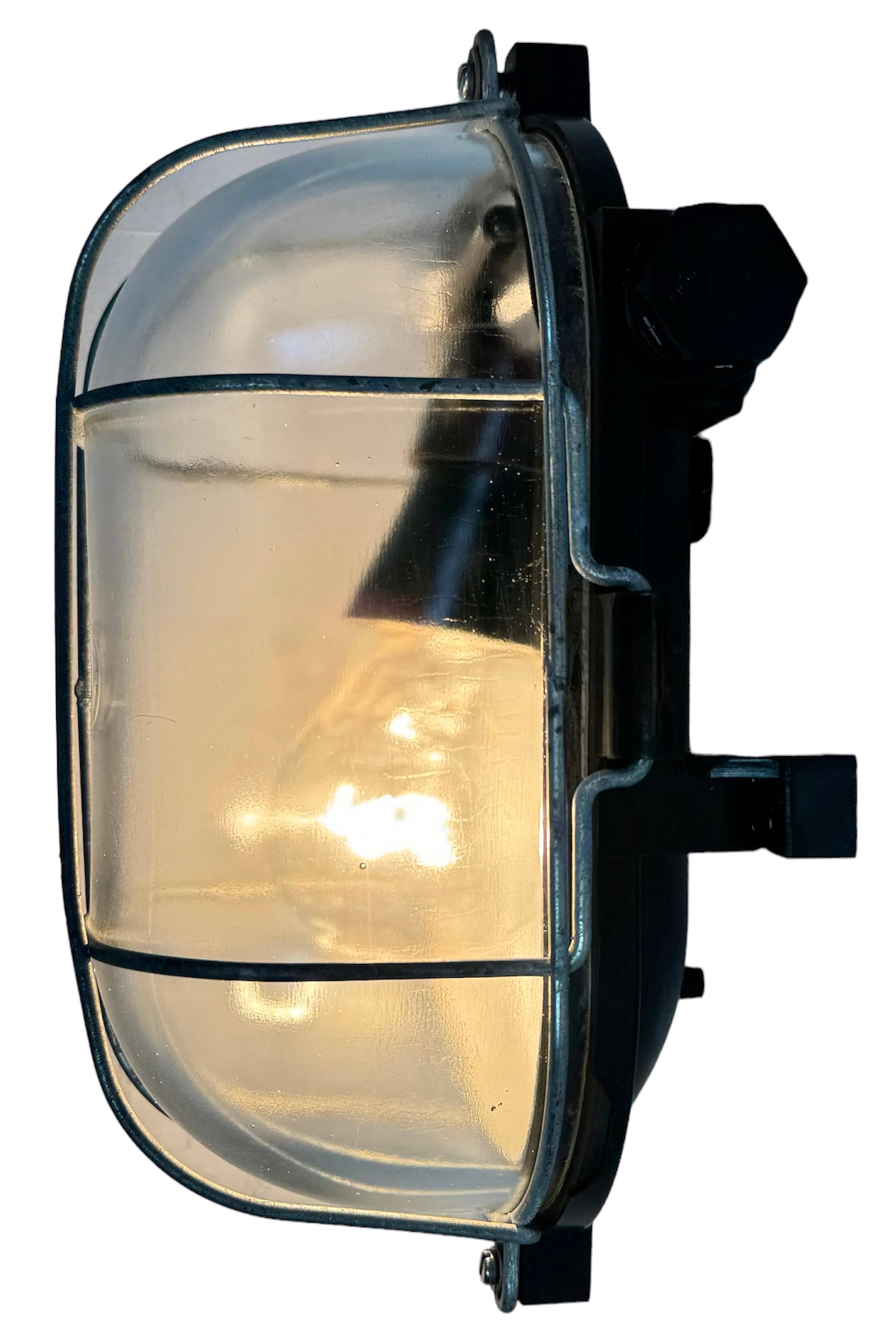 Vintage industrial brown bakelite wall lamp made in former Czechoslovakia during the 1960s. It features a bakelite body, a clear glass cover and iron grid.The socket requires standard E 27/E 26 light bulbs.  Weight of the lamp is 1 kg.