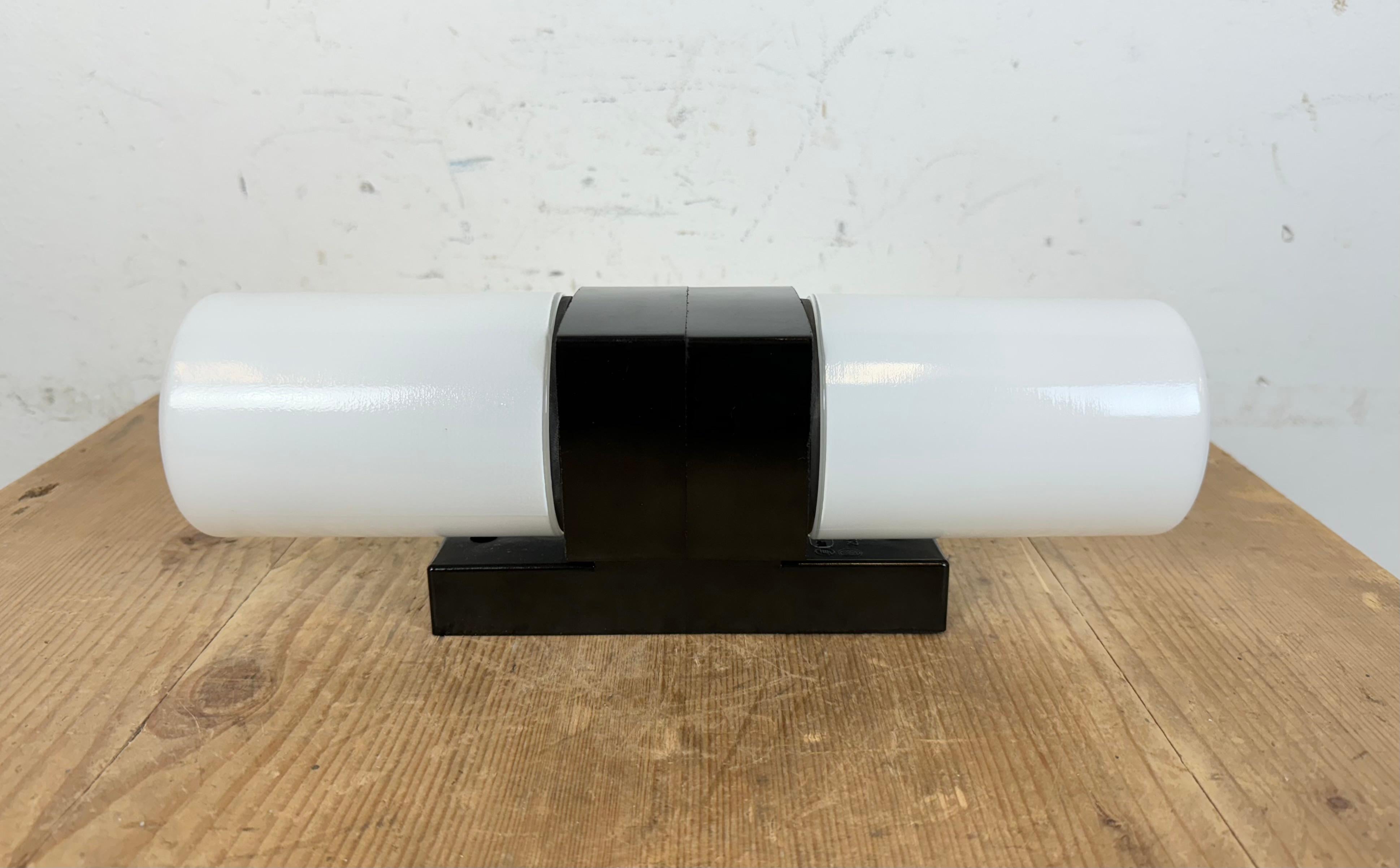 Vintage industrial brown bakelite wall lamp made in former Czechoslovakia during the 1960s. It features a bakelite wall mounting and two milk glass covers. The sockets require two E 14 light bulbs.  Weight of the light is 0,9 kg.