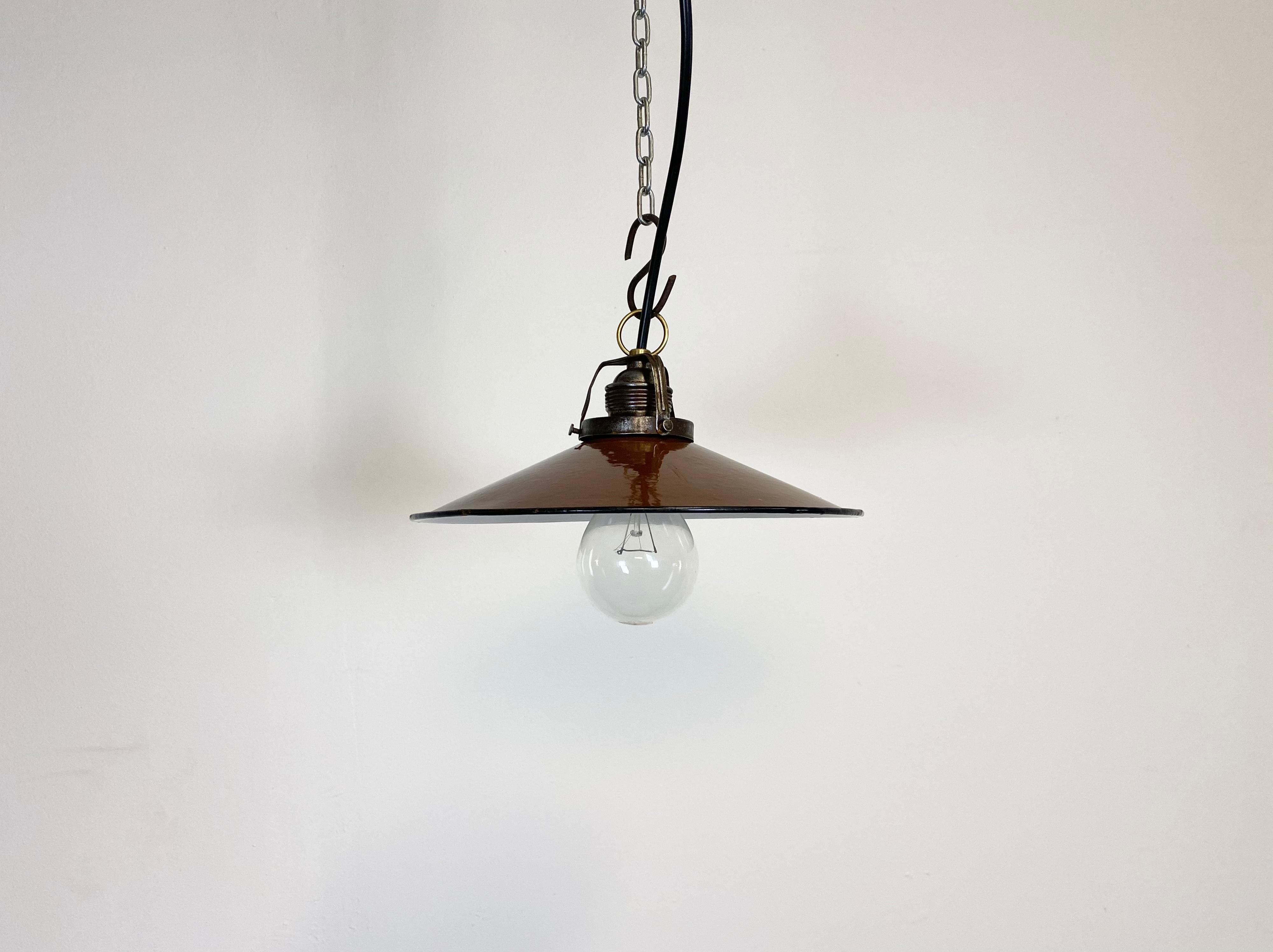 Vintage industrial enamel pendant lamp from the 1930s. It features brown enamel shade with white enamel interior and brass top. Original porcelain socket requires E 27 light bulbs. New wire.