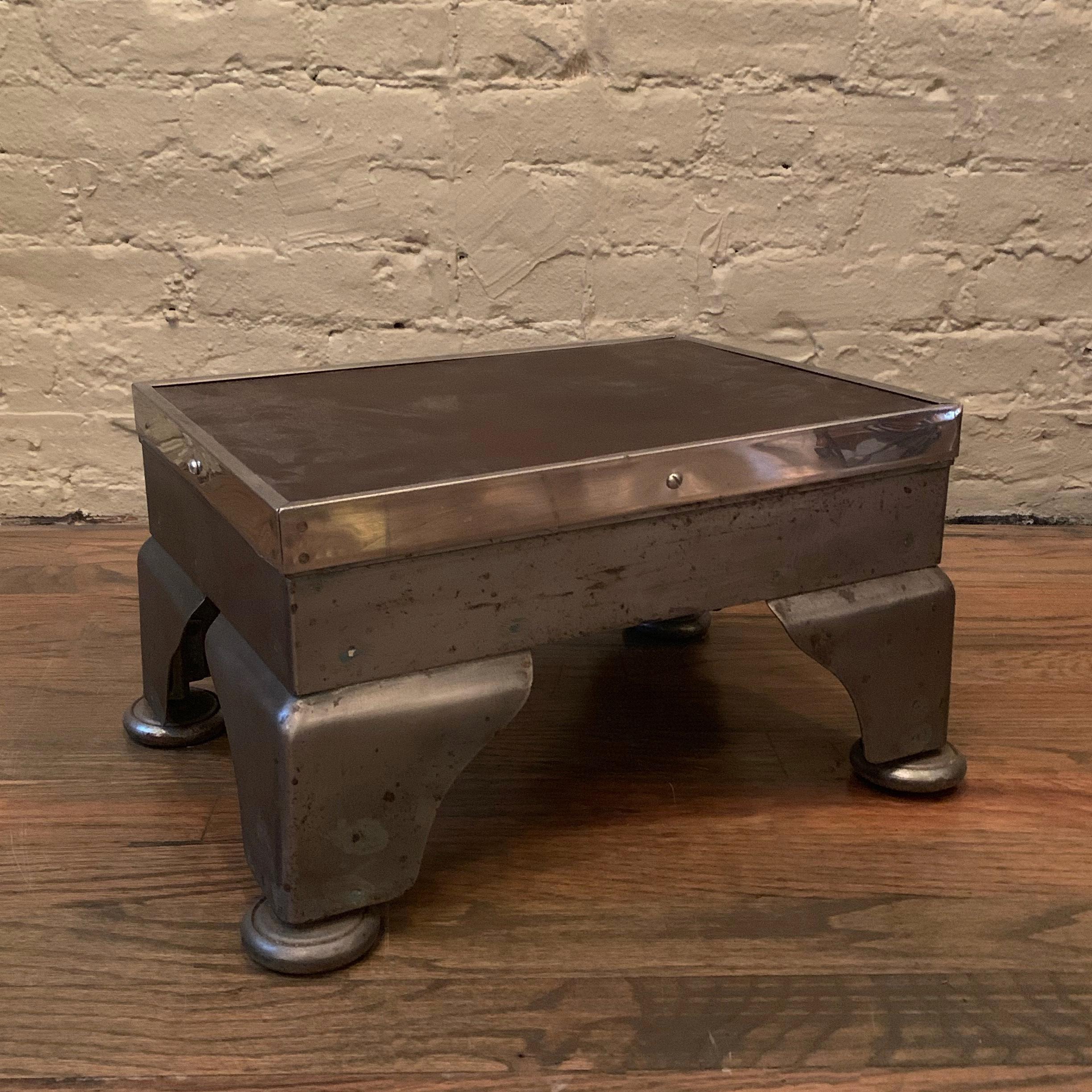 Industrial, machine-age, hospital, foot stool features a brushed steel base with chrome trim and leather top.