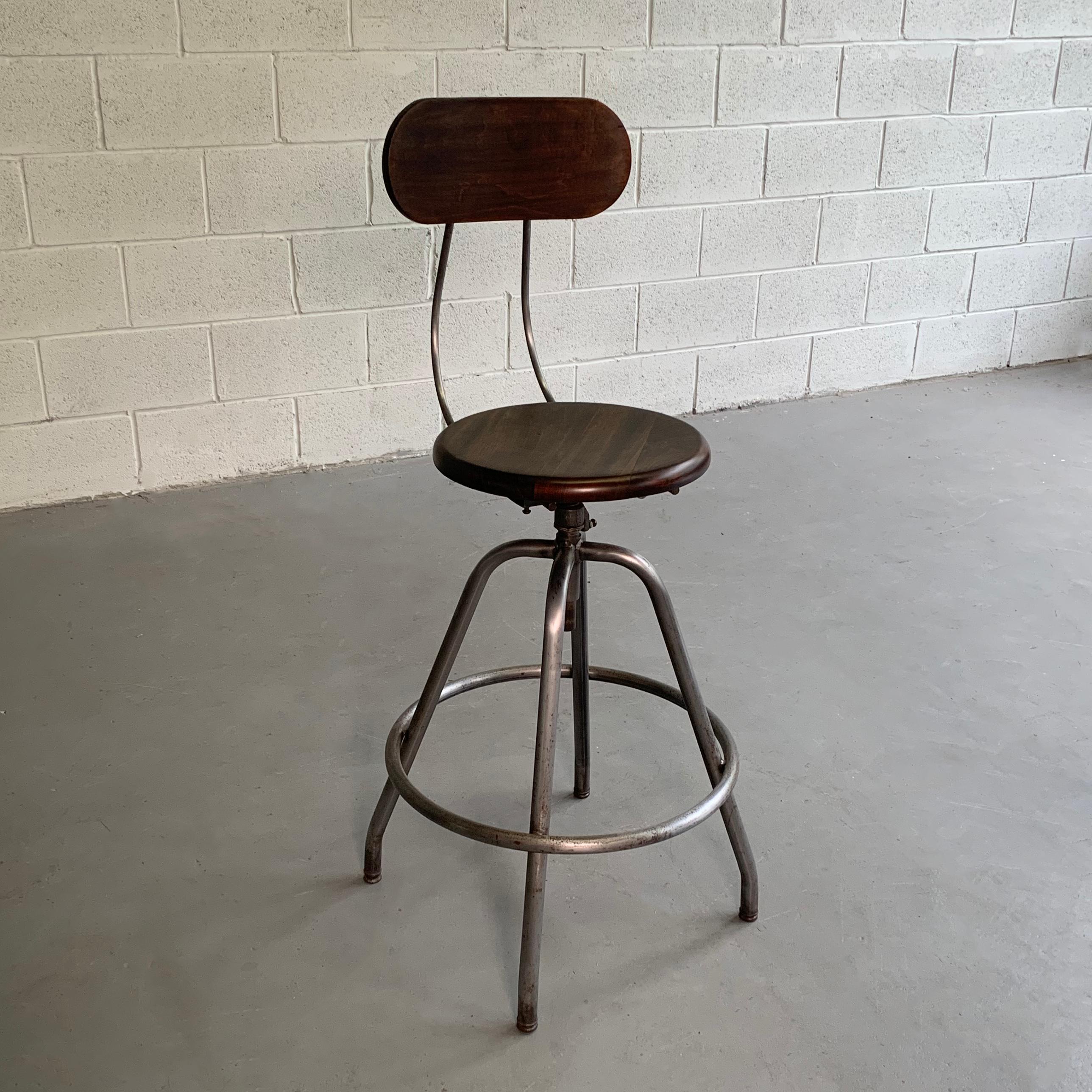 Industrial, drafting stool features a brushed steel frame with a maple back and 14 inch round, swivel seat that is height adjustable from 27.5 - 31 inches.