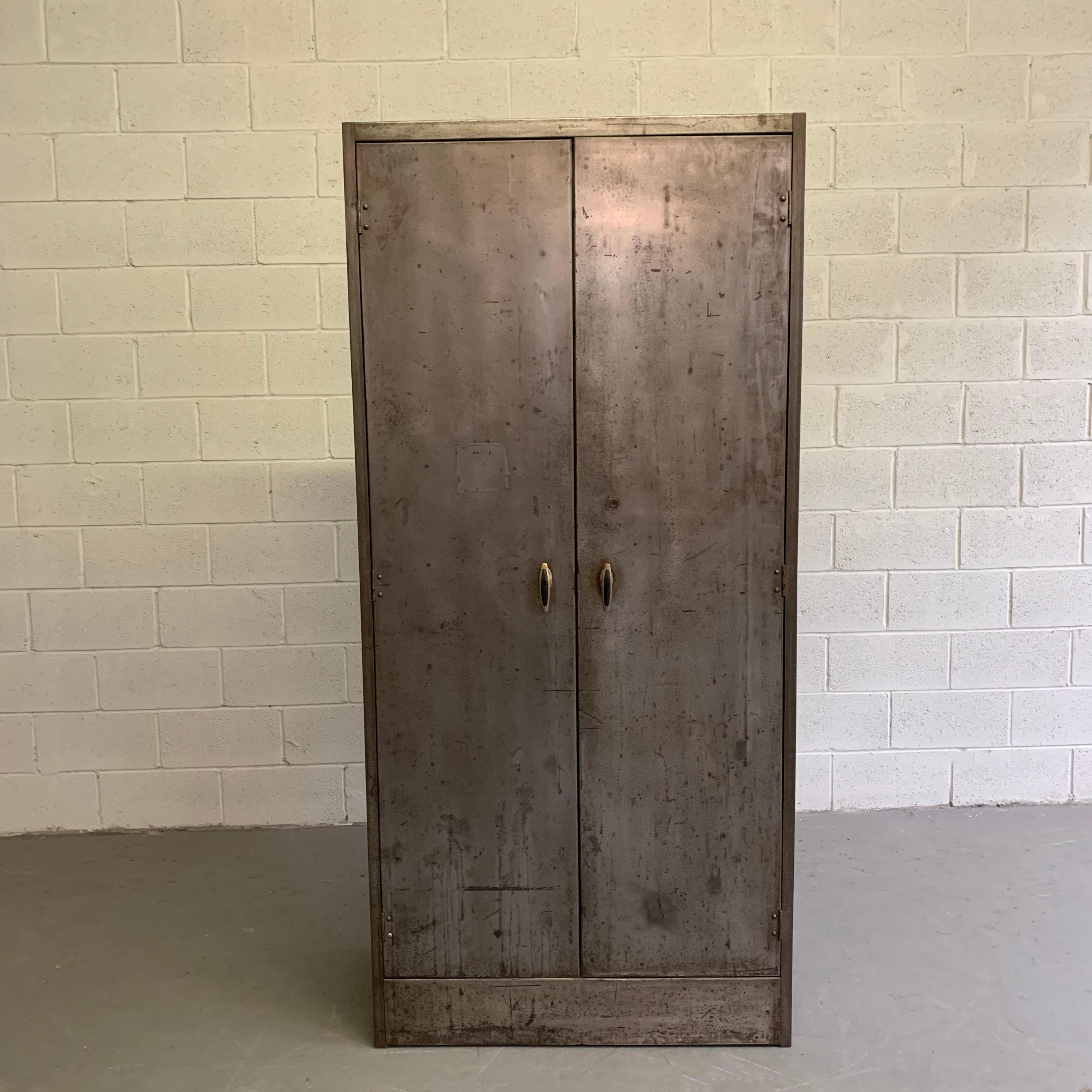 Tall, industrial, brushed steel, double door cabinet can be used as an armoire or wardrobe. The interior retains its rustic original patina with adjustable shelves. Interior dimensions are 36 x 17.25 x 69.75.