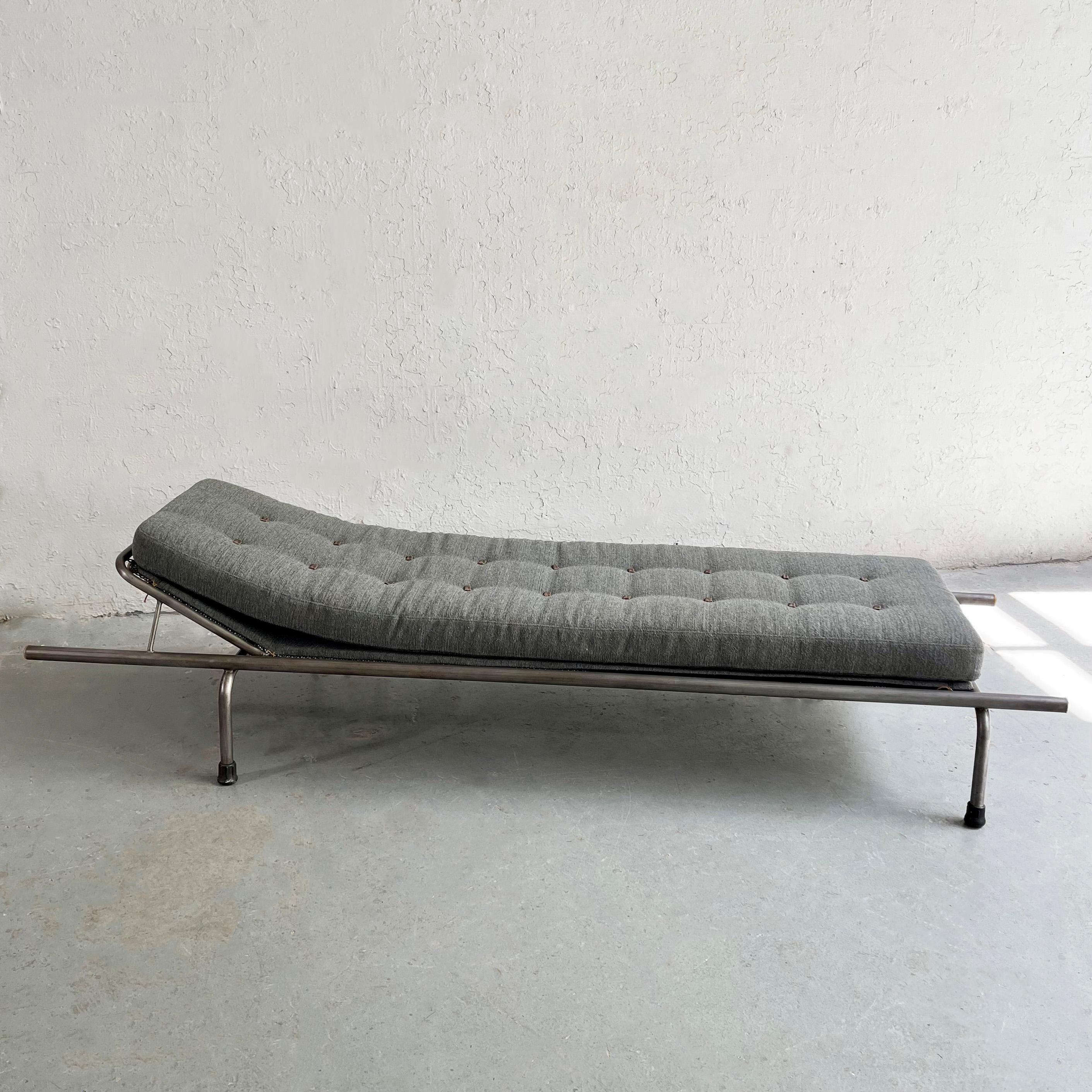 Industrial, tubular steel frame, chaise longue with segemented chenille cushion with custom leather tie buttons resting on an upholstered chenille backing and mesh frame.