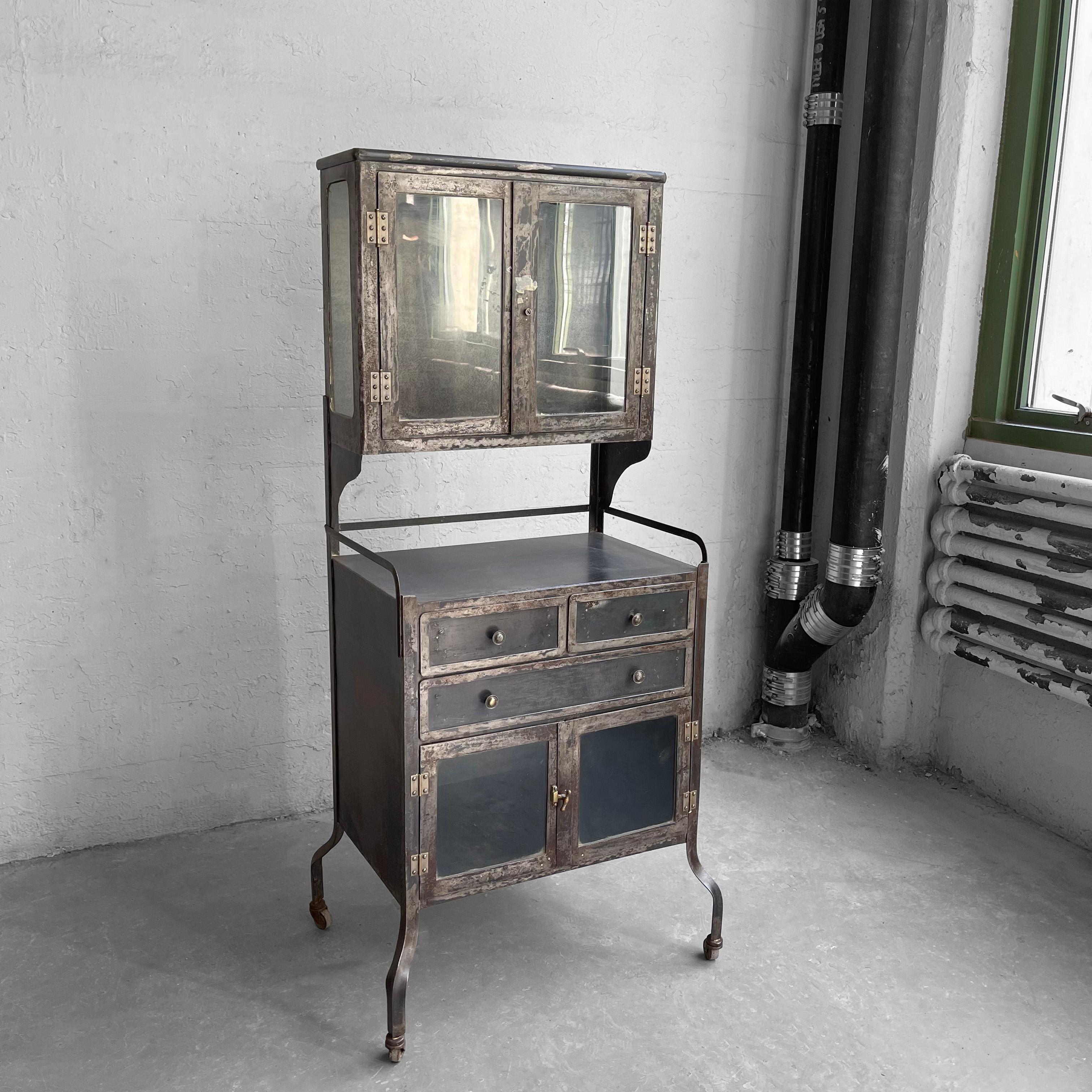 Early 20th century, antique, industrial, brushed steel, dentist apothecary cabinet features drawers and glass front storage on the bottom and recessed, glass front display storage on top. Exterior and interior are brushed steel. Two glass shelves