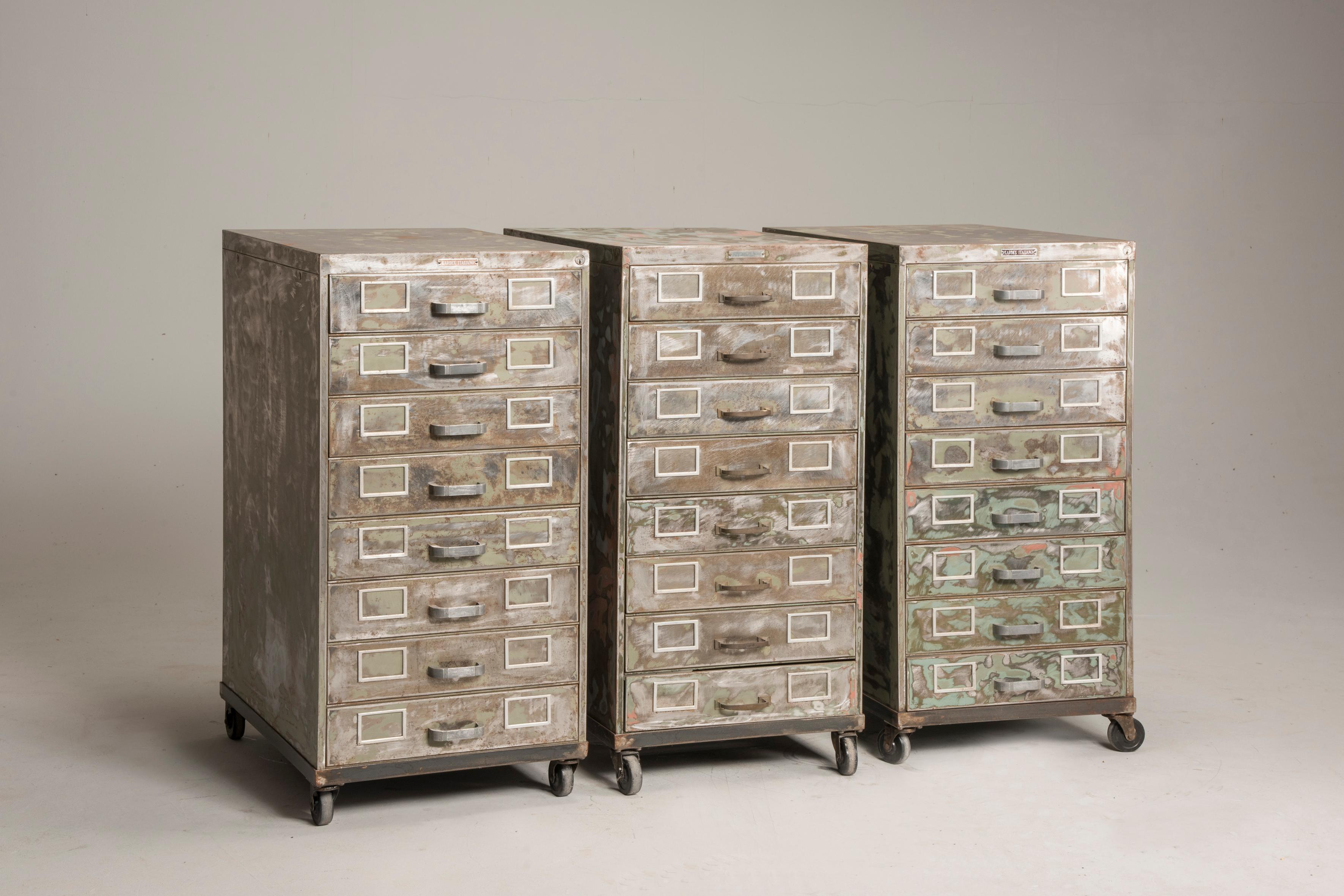 Industrial brushed steel distressed look wheeled filing cabinets.
We propose three filing cabinets with drawers made of brushed steel, they show previous lacquer distressed layer. Each cabinet has eight drawers and each one of them has space for