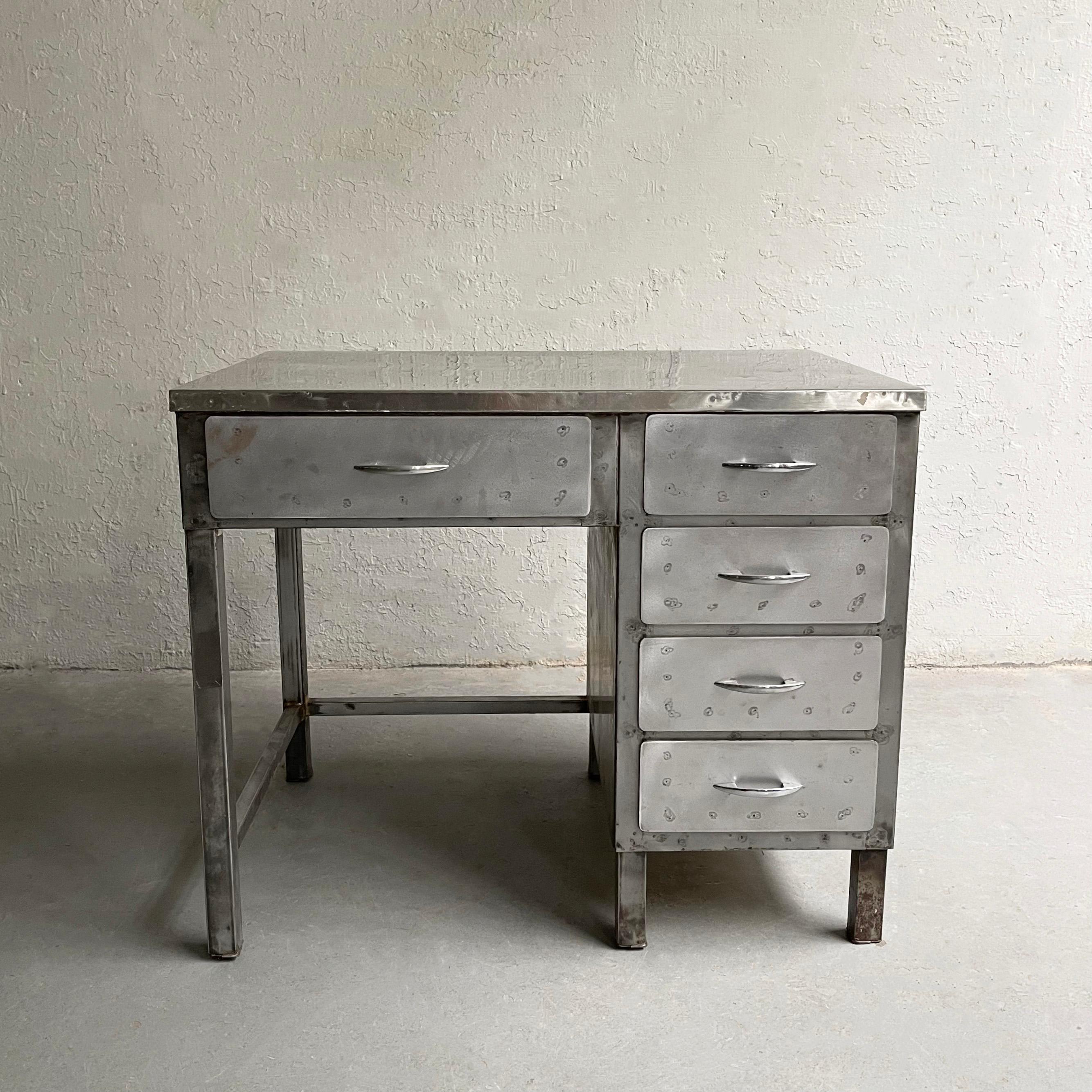 Midcentury, industrial, factory desk features a brushed steel body with stainless steel top and handles and is presentable on the back as well. The desk's chair opening is 19.5 x 23 inches.