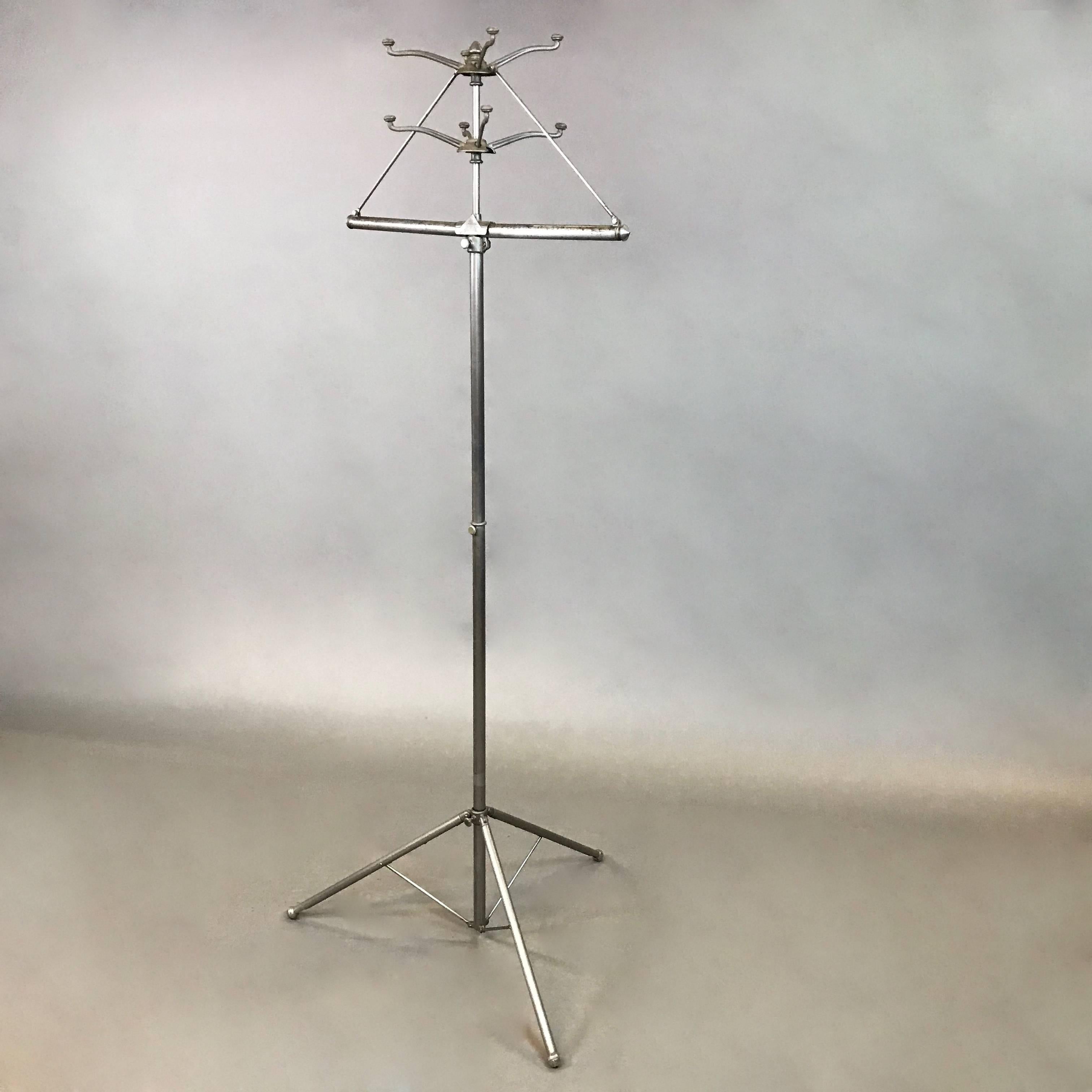 Industrial, brushed steel, folding, coat and garment rack features a tripod base, a 26 inch hanging cross bar for hanging garments and four hooks.