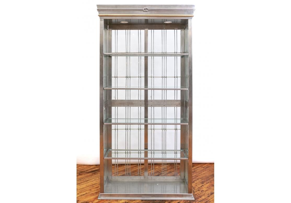 An Industrial Style brushed steel and glass etagere with illuminated interior and four glass shelves all with fine beveled edge. The etagere with cable elements that are looped around the horizontal supports. The crown with a knotted element and