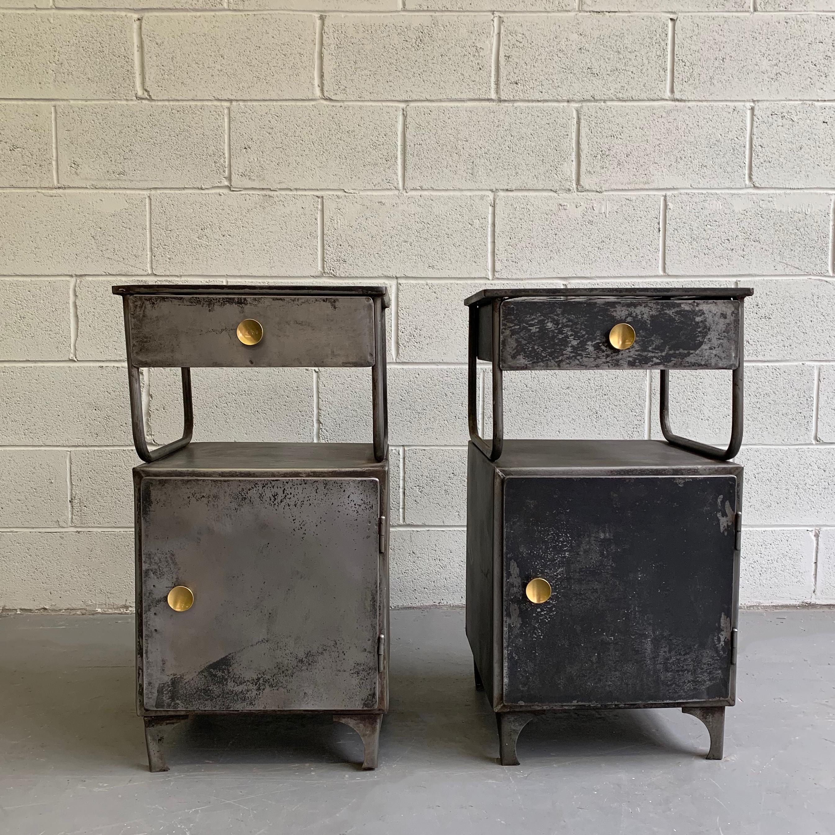Pair of early 20th century, industrial, brushed, patinated, steel, 2-tier, hospital nightstands feature great storage on the bottom and drawers on top with brass button pulls and painted light blue interiors. The cabinets also make excellent