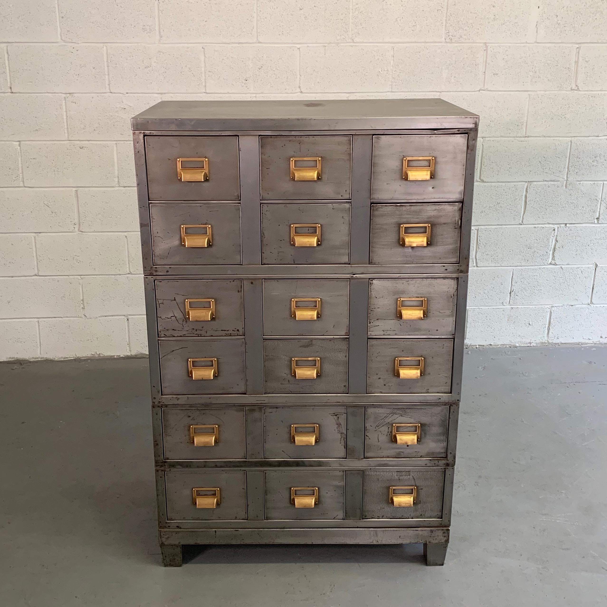 Industrial, brushed steel, office cabinet features 18 index size drawers with brass hardware that measure 9 width x 6 height inches with interiors of 8 width x 16 deep. There are 3, modular, stacked units that comprise this cabinet.