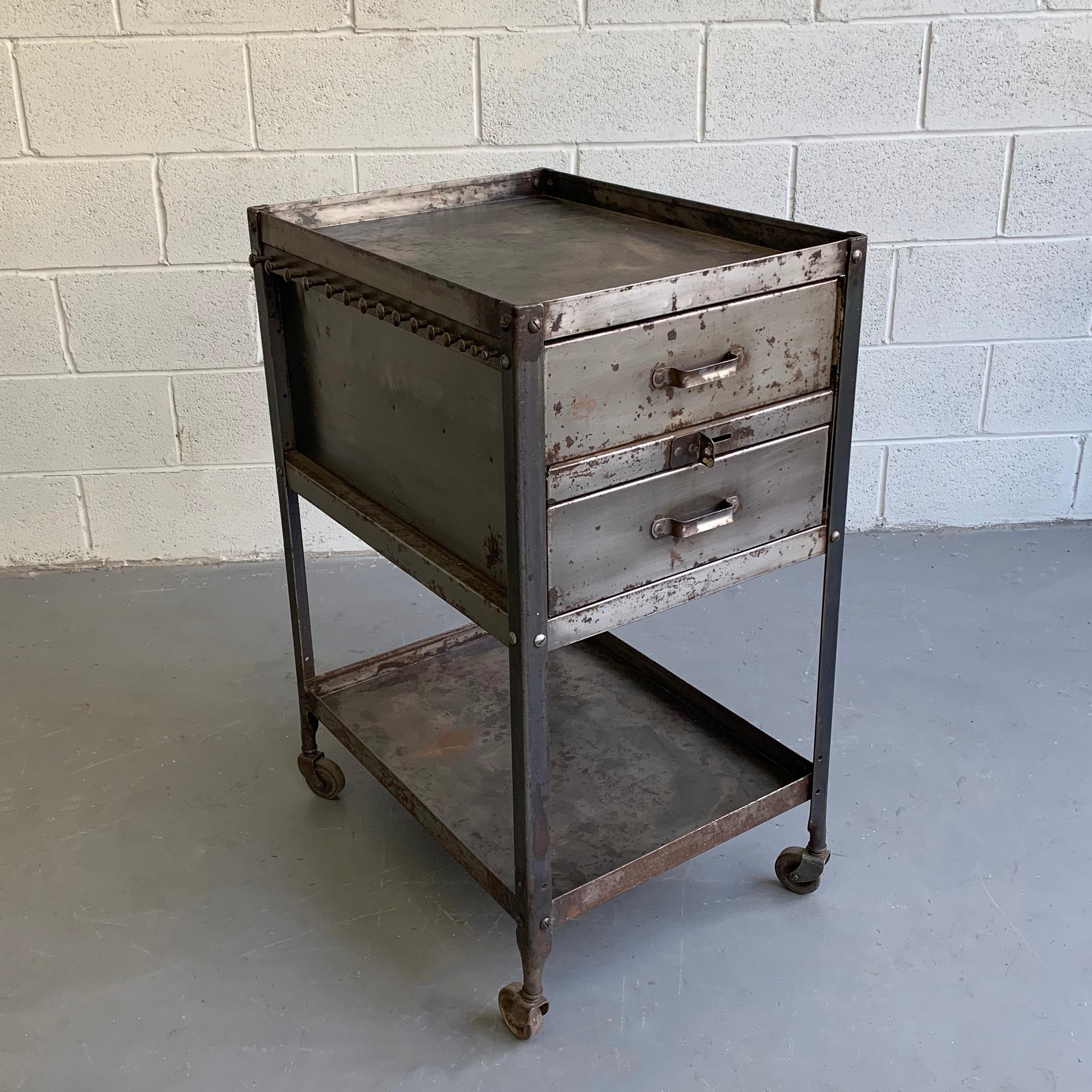Midcentury, industrial, brushed steel, rolling, tool caddy by Lyon features drawers on top and open storage below with pegs on one side for hanging. The caddy can be repurposed in many ways and can make a great kitchen piece. Interior of drawers is