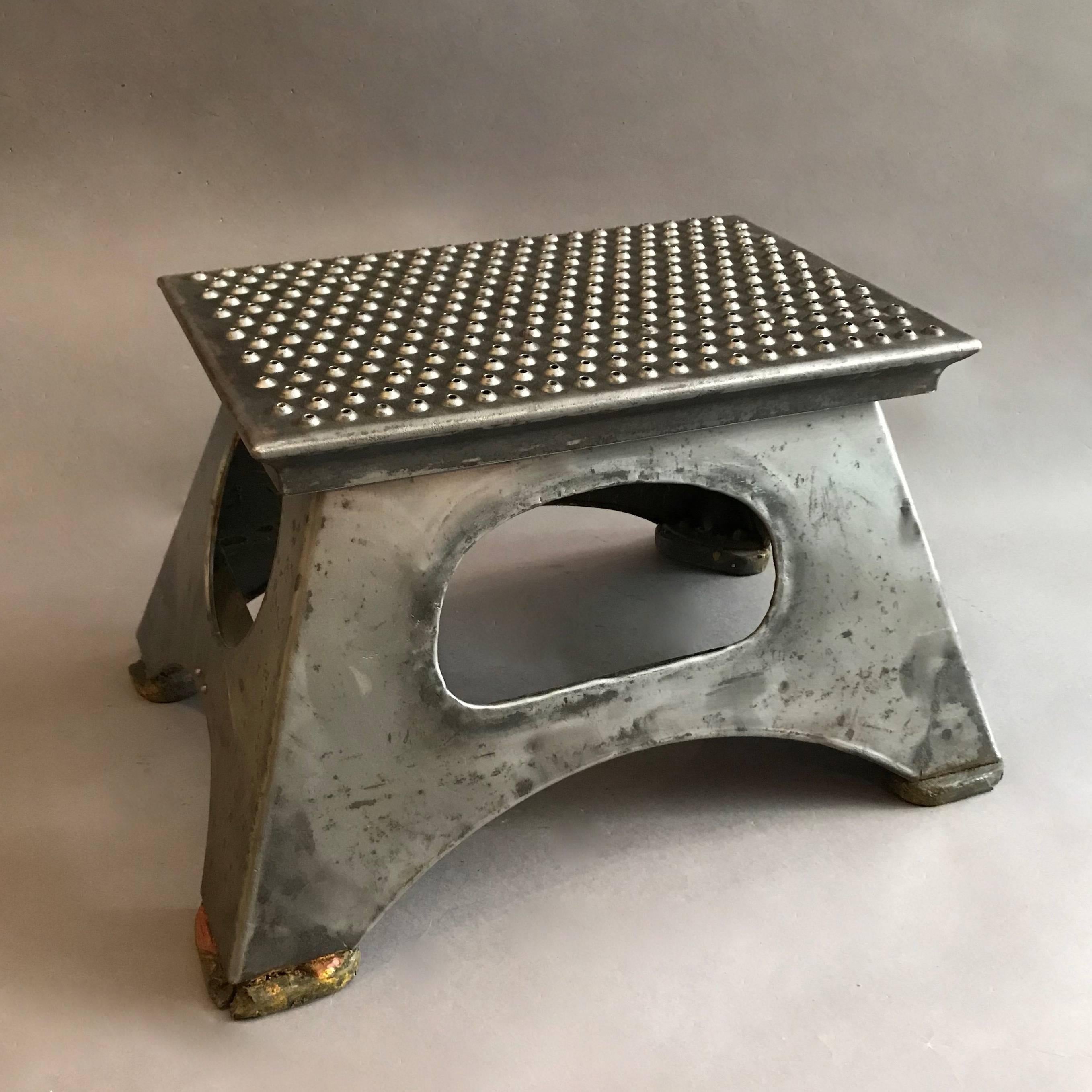 Industrial, early 20th century, brushed steel, train conductor, step stool features open handles on all sides and a perforated slip grip top. The top tapers to 12 inches x 8 inches.