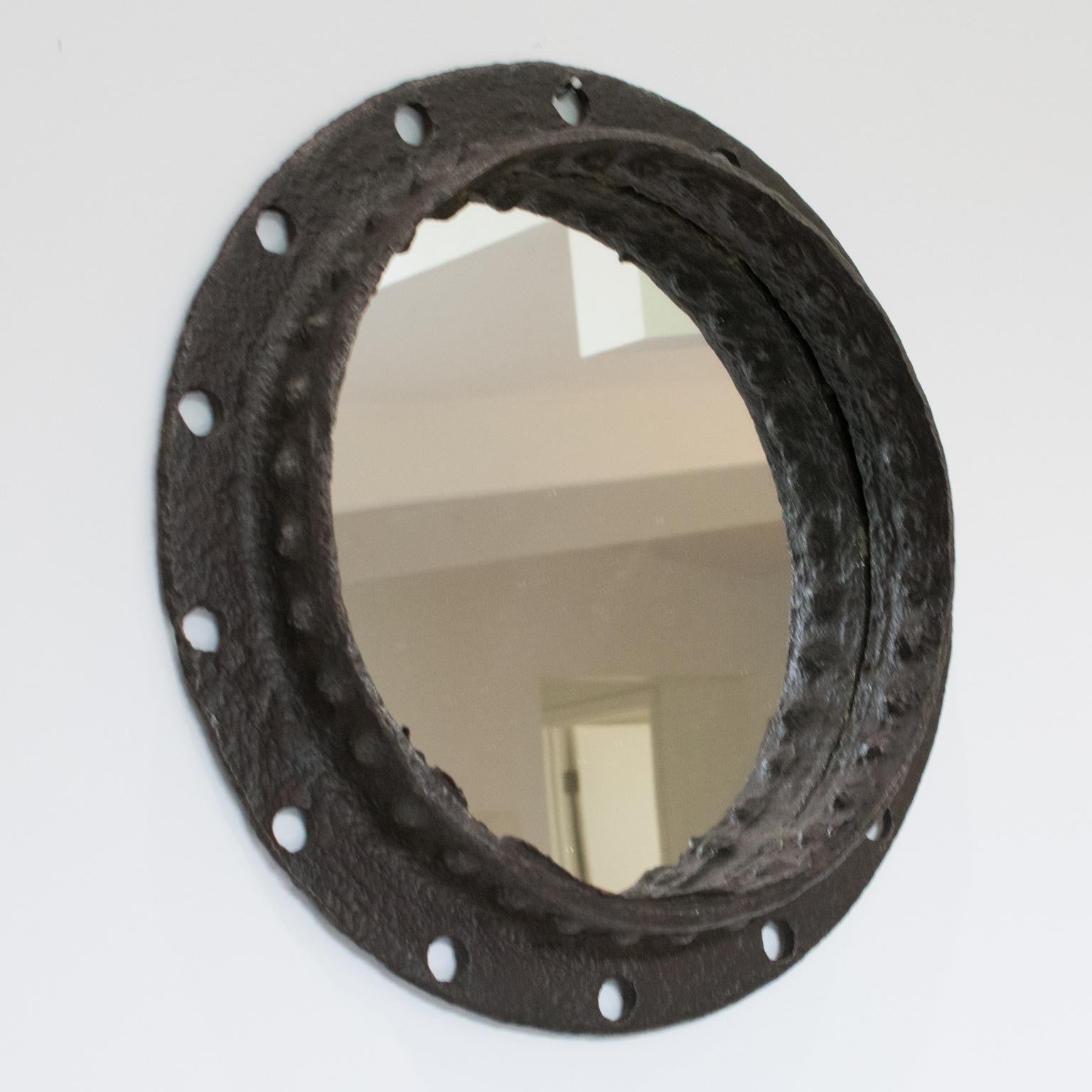 This stunning brutalist industrial wrought iron wall-hanging mirror was crafted in France. The massive round shape boasts an incredible metal framing with its original gunmetal patina. This mirror is a reclaimed salvage piece from an industrial