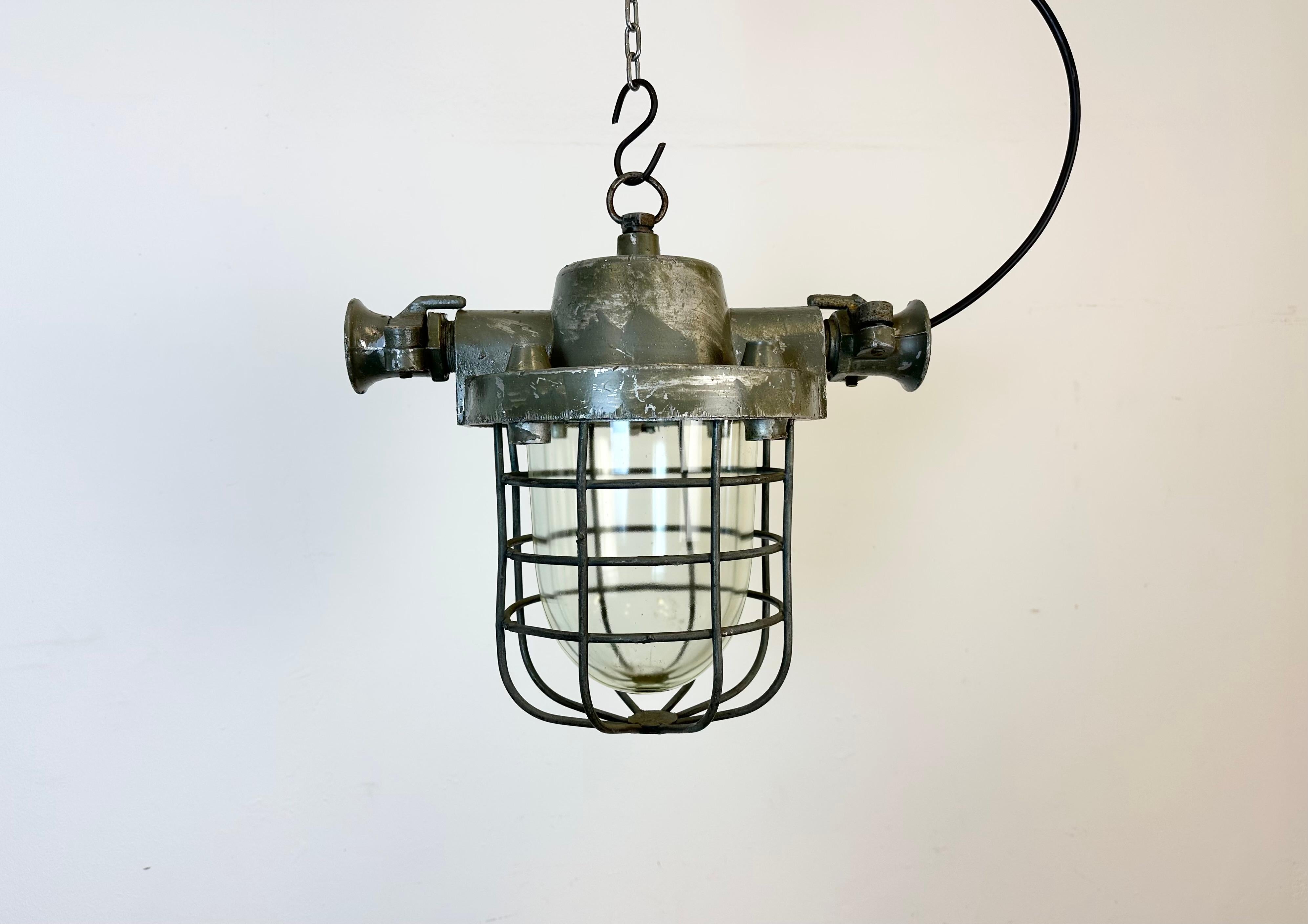 Industrial exposion-proof hanging lamp made in Poland during the 1960s. These lamps were used in factories where was a danger of gas or dust explosion. It features a cast aluminium body, a clear glass cover an an iron grid. The porcelain socket