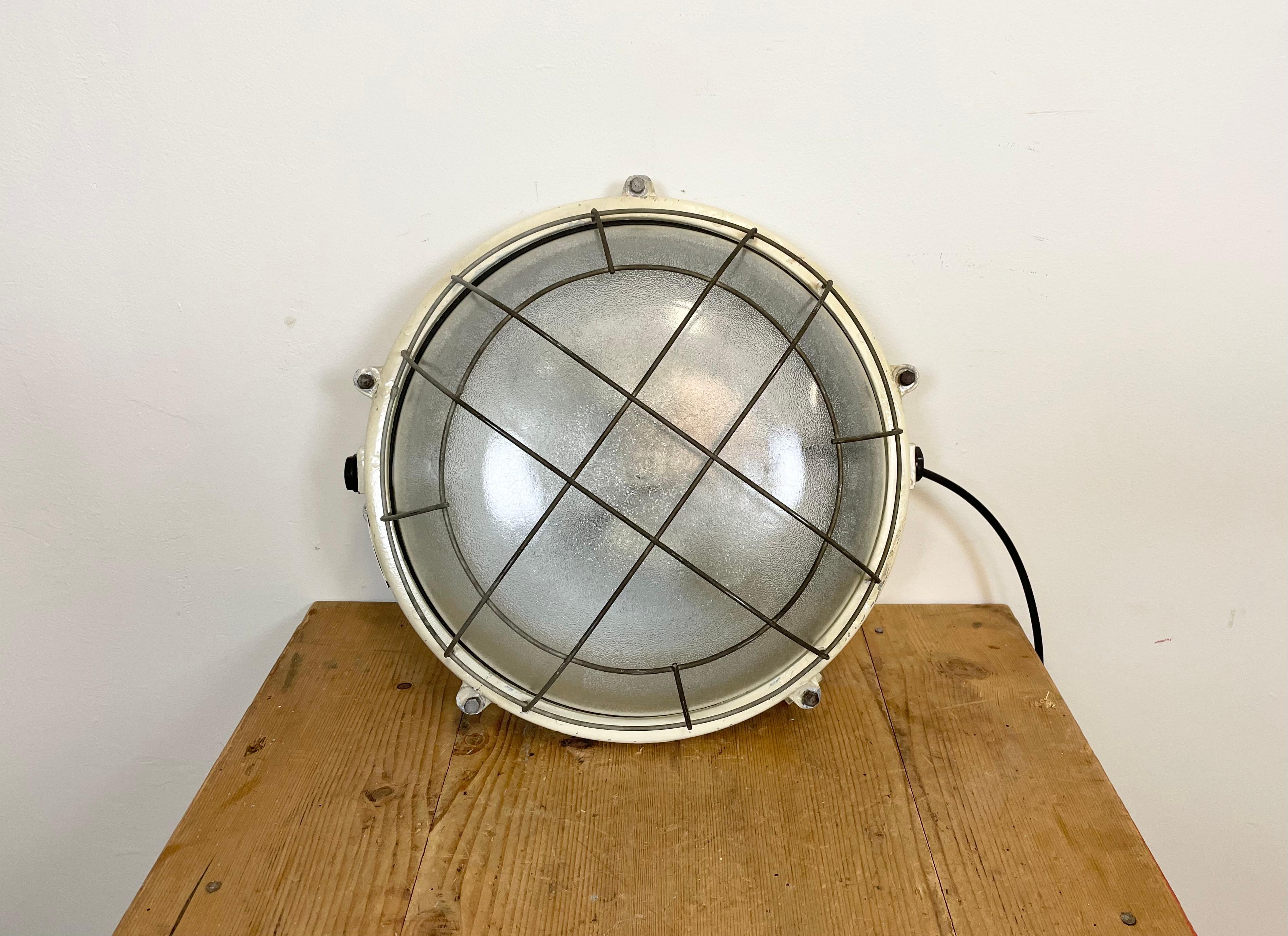 Vintage industrial cast aluminium wall lamp made by Elektrosvit in former Czechoslovakia during the 1970s. It fetures a cast aluminium body, frosted curved glass cover and iron grid. Two porcelain sockets require E 27 light bulbs. It can be also