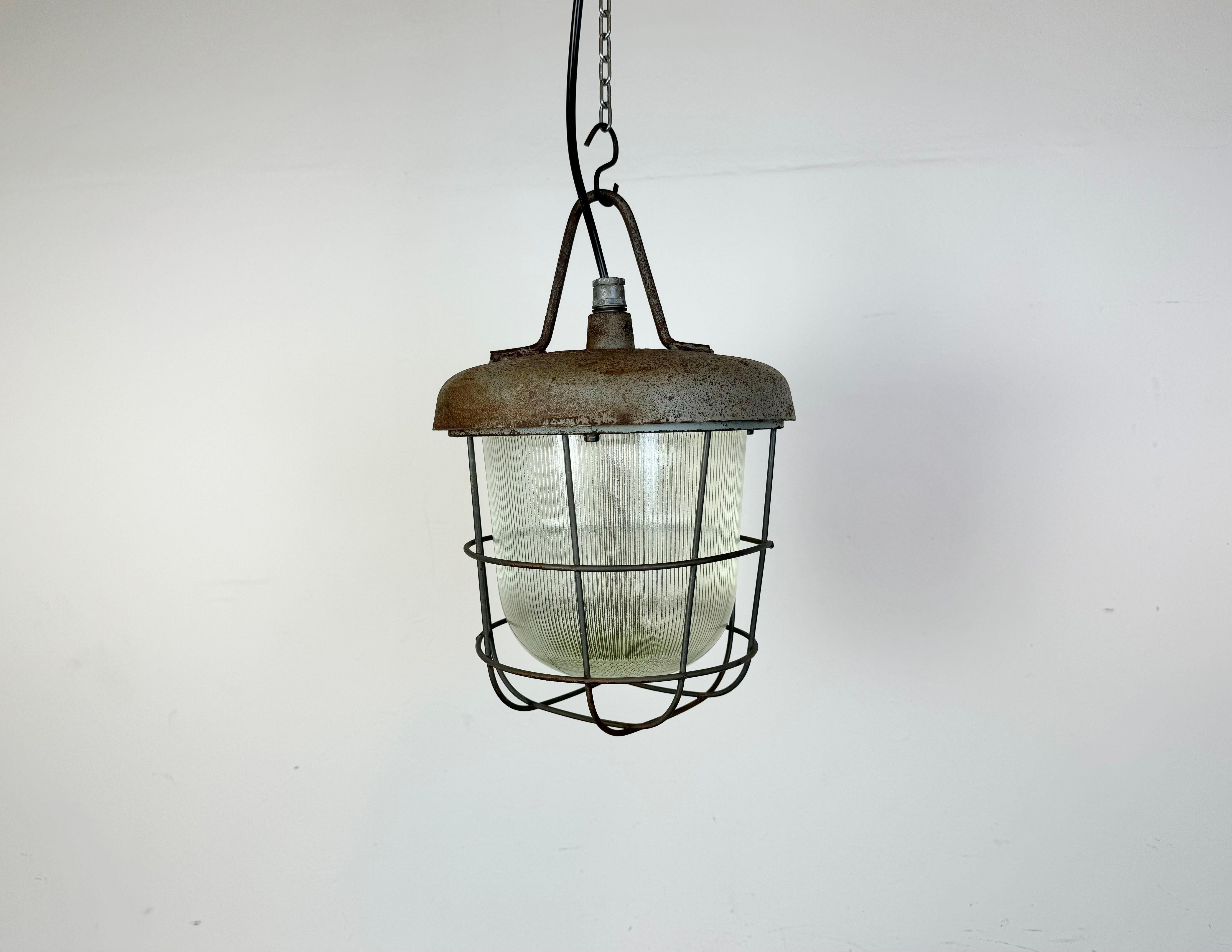 Industrial factory hanging lamp made by Polam Wilkasy in Poland during the 1960s.It features a cast iron top, a striped glass cover and an iron grid. The porcelain socket requires standard E27 / E26 lightbulbs. New wire. The weight of the lamp is 7