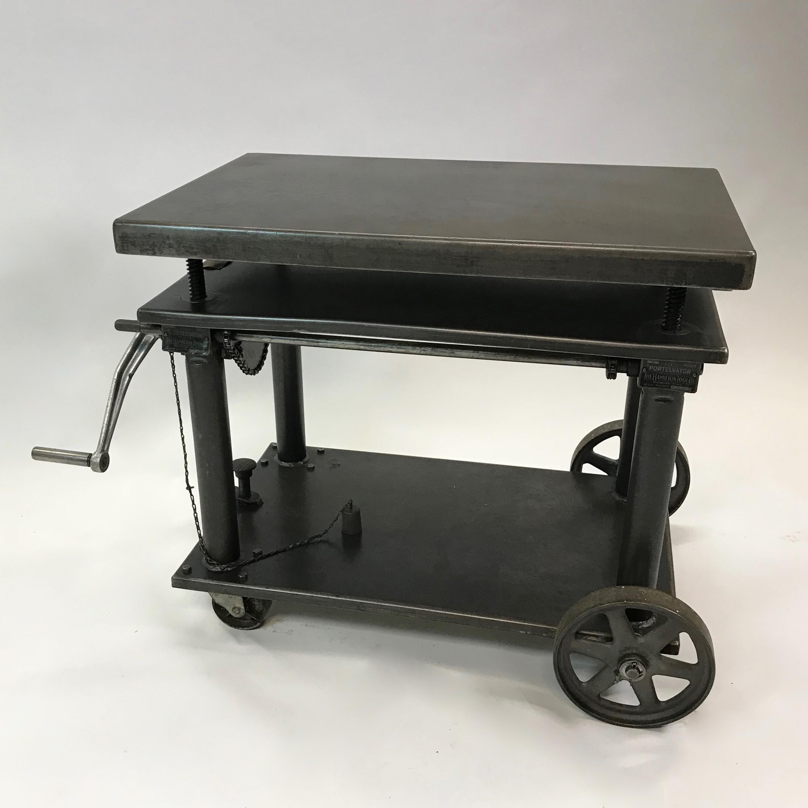 American Industrial, fully functional, iron and steel, heavily reinforced, hand-crank, mobile factory cart or die table manufactured by Hamilton Tool Co., Hamilton, Oh. is height is adjustable from 25 - 39 inches. This portable elevating table or