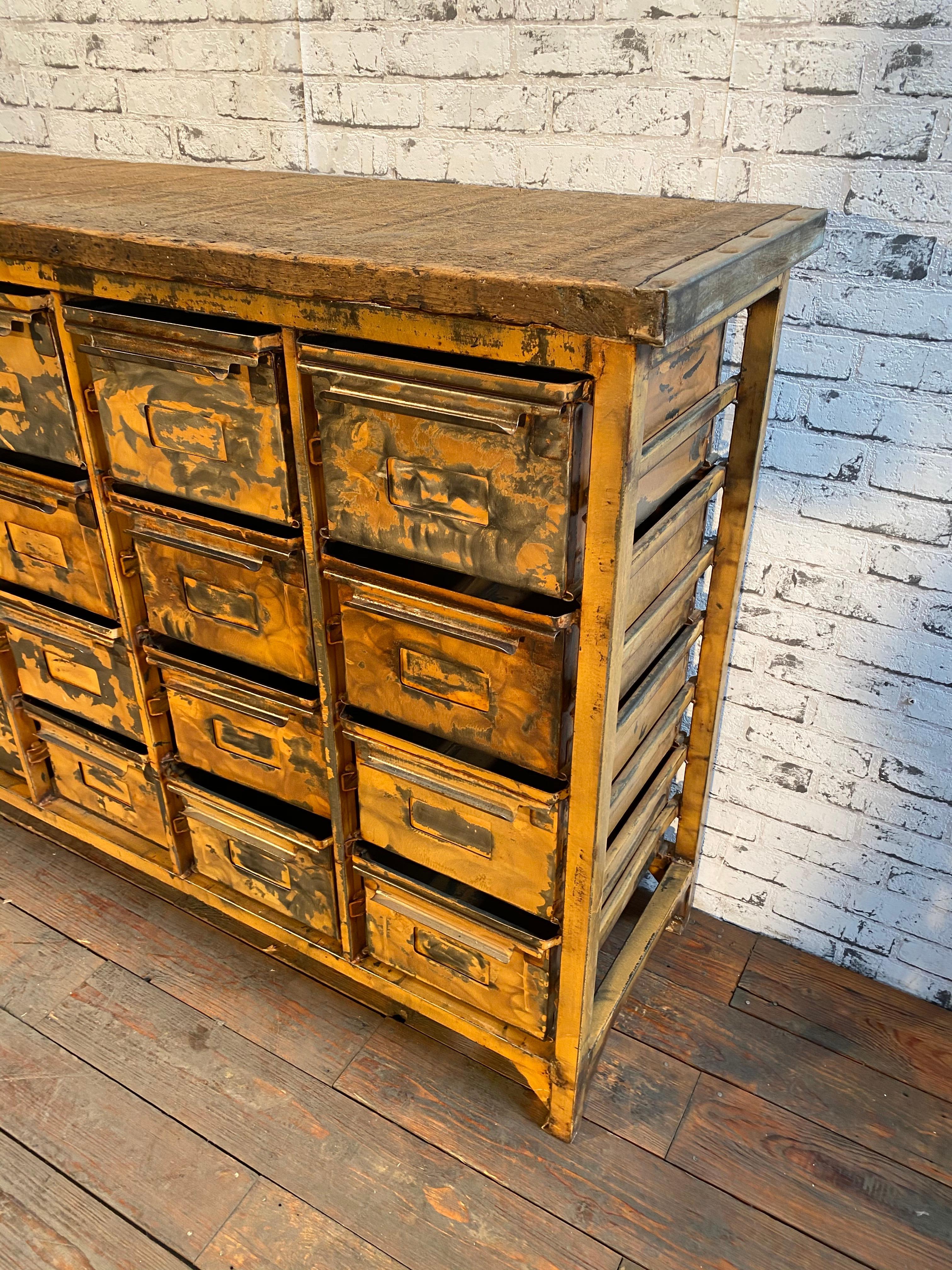 This vintage industrial iron chest of drawers was made during the 1950s. It features an iron construction, an old wooden top, and 16 metal drawers. 
Additional dimensions:
- Drawer dimensions: Width 26 cm, depth 38 cm, height 19 cm 
- Weight: 80