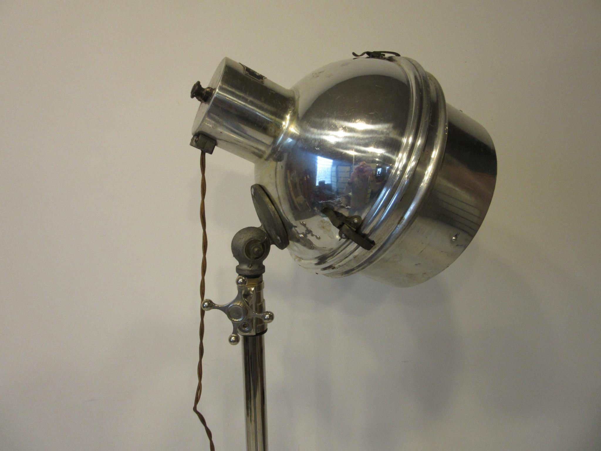 A industrial nickel chrome-plated adjustable floor lamp a large lamp head with a mercury toned reflector behind the bulb, big stylized knobs and great scissor base with built in feet to protect your floors. Has the repro old school looking