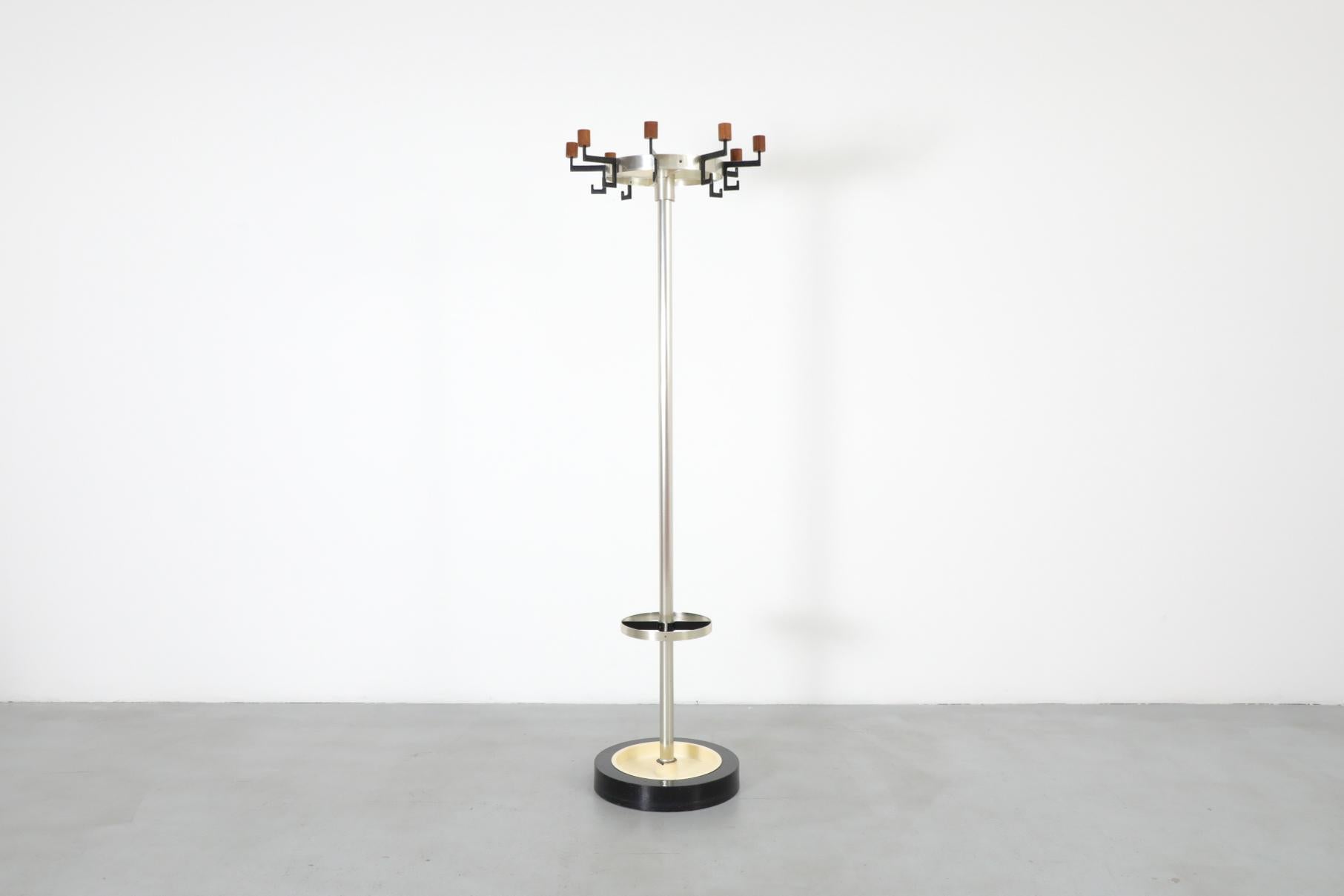 Appendiabiti industriale in piedi con ganci in teak, un portaombrelli con vaschetta integrata e una pesante base nera zavorrata. Design elegante e funzionale con corona superiore girevole. In condizioni originali, con segni di usura e graffi dovuti