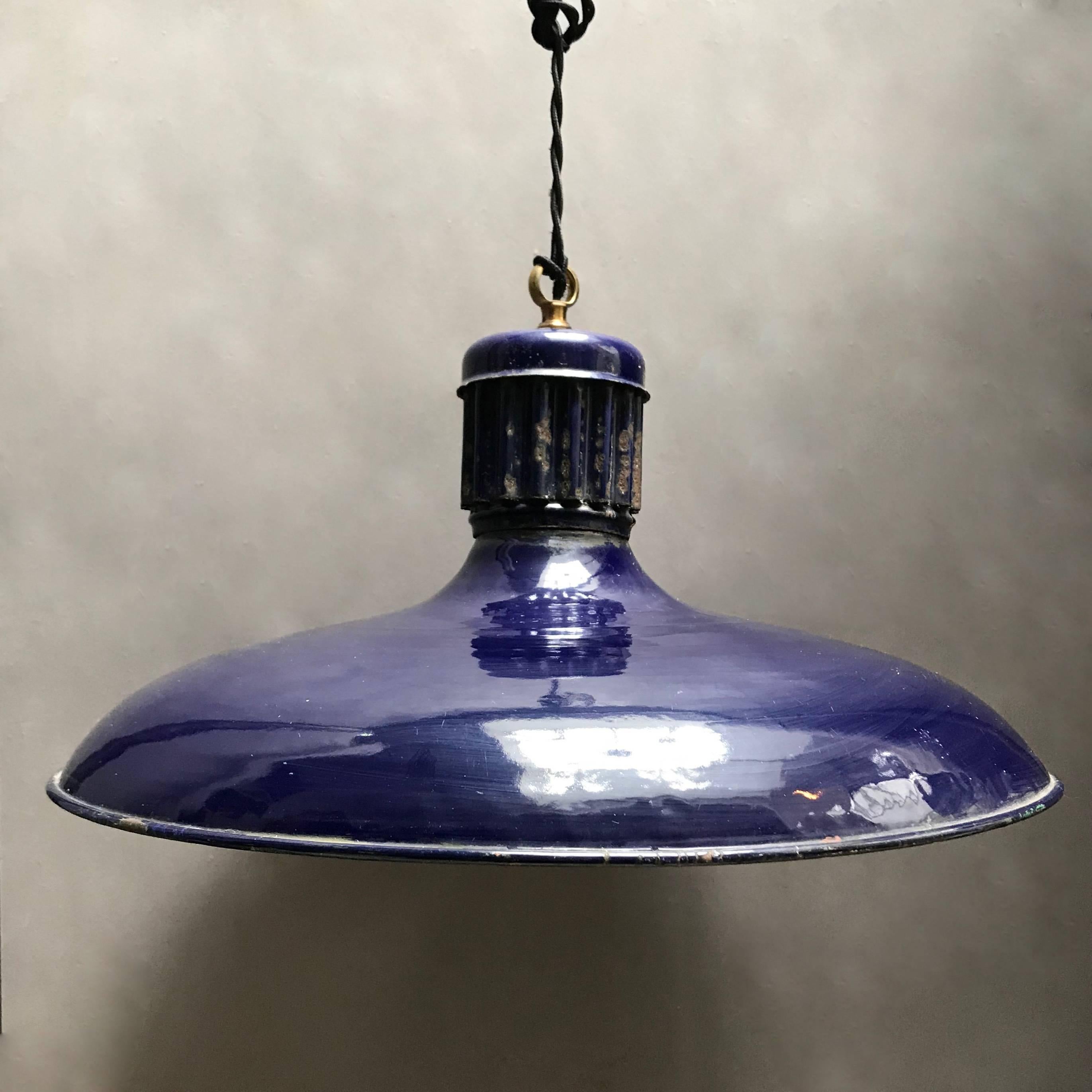 Industrial, railroad station pendant light features a deep cobalt blue enamel exterior with ribbed fitter and white interior is newly wired with 36 inches of braided black cloth cord to accept up to a 200 watt bulb.