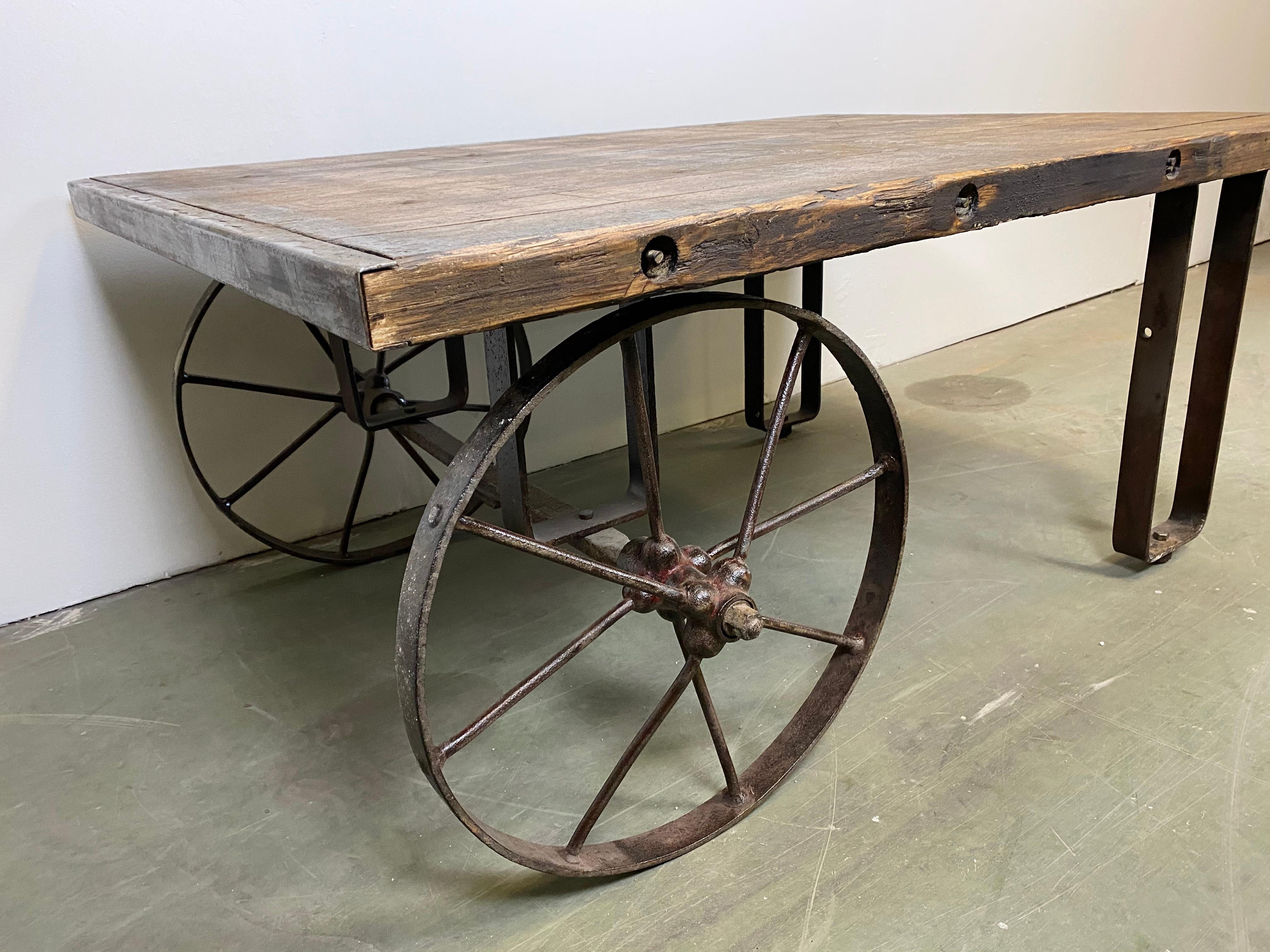 This is an industrial coffee table from the 1950s. It features cast iron legs and a solid old wooden plate with very nice patina. Weight: 75kg.