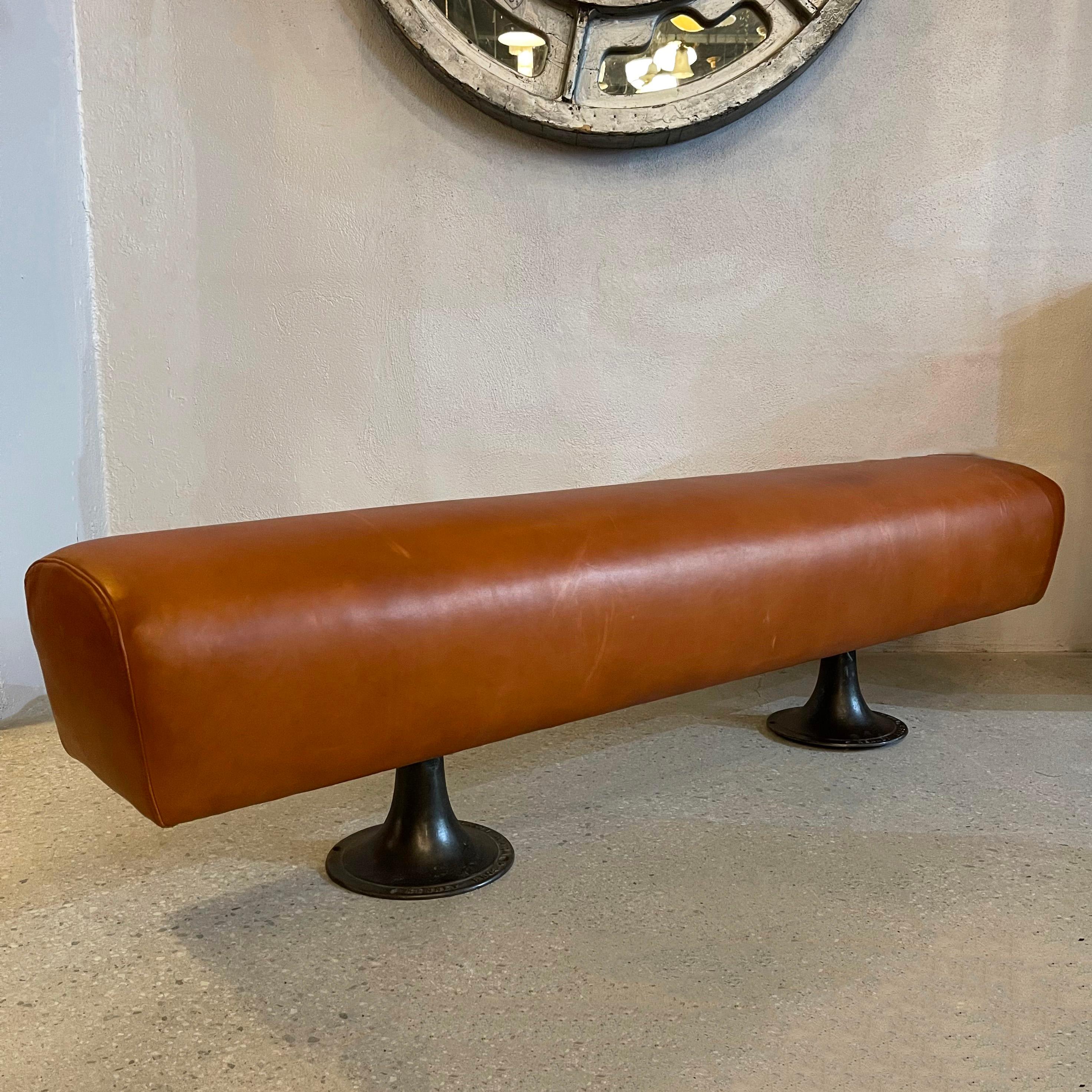 Custom, industrial, pommel horse bench features a 1950's pommel horse newly covered in supple, russet leather paired with antique cast iron factory pedestal legs. This one-of-a-kind bench is composed of vintage and antique components, custom
