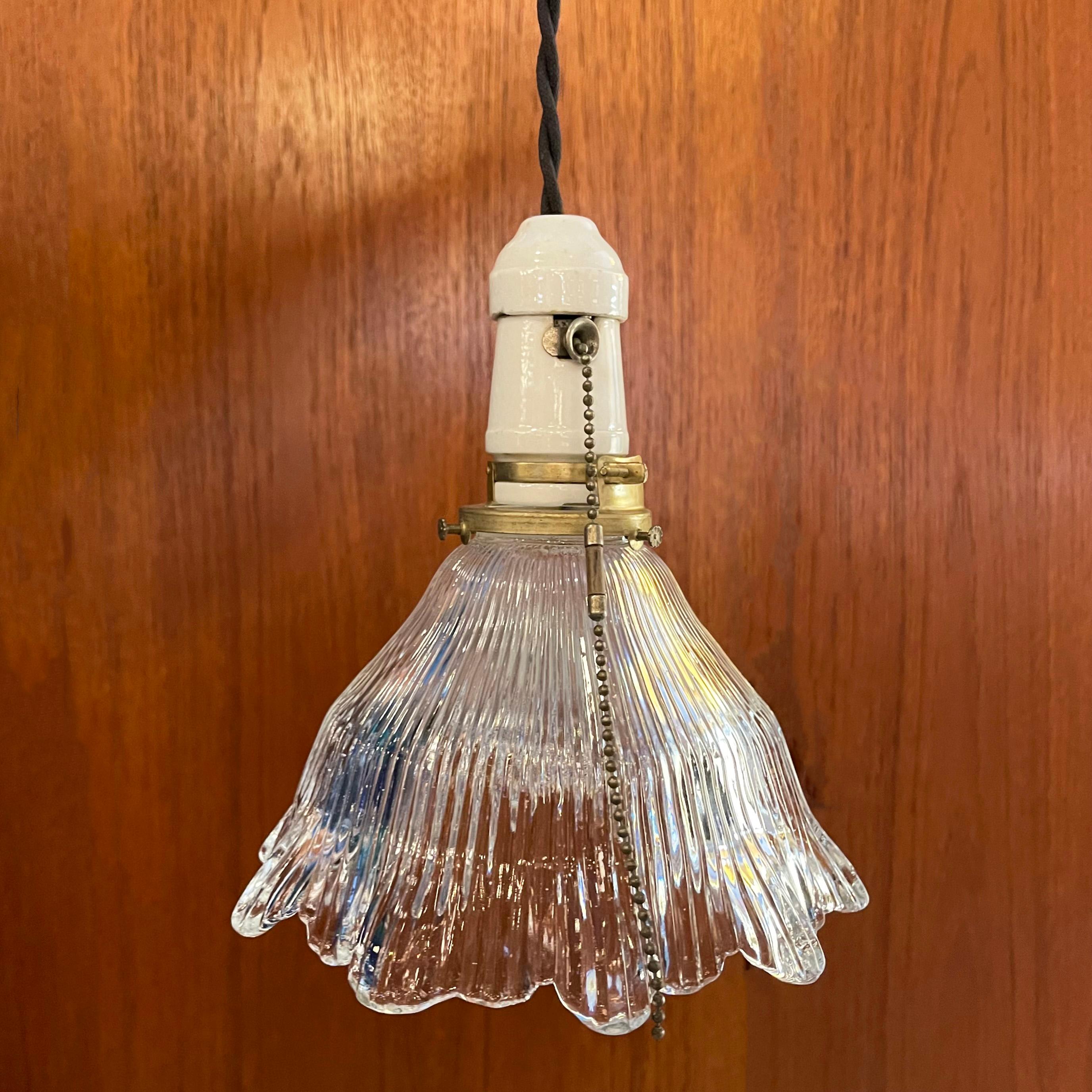 Industrial pendant light features a cut glass shade with irregularly scalloped edge with porcelain pull-chain socket and brass fitter. The pendant is newly wired with 40 inches of braided cloth cord.