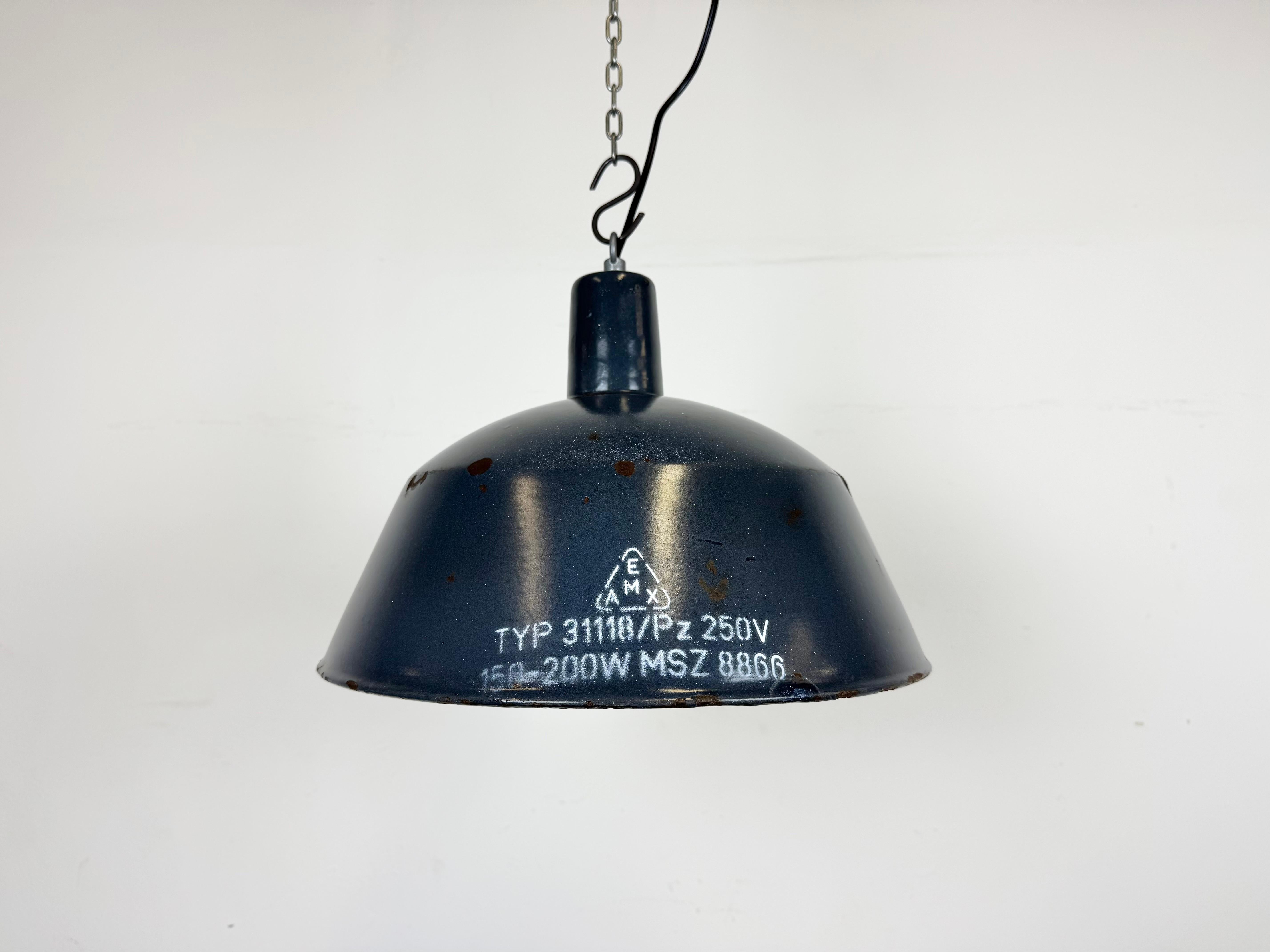 Questa lampada industriale è stata prodotta da EMAX in Ungheria negli anni '60. Presenta un paralume smaltato blu scuro con interno smaltato bianco e piano in ferro. La nuova presa in porcellana richiede lampadine E 27/ E26. Un nuovo cavo. Il peso