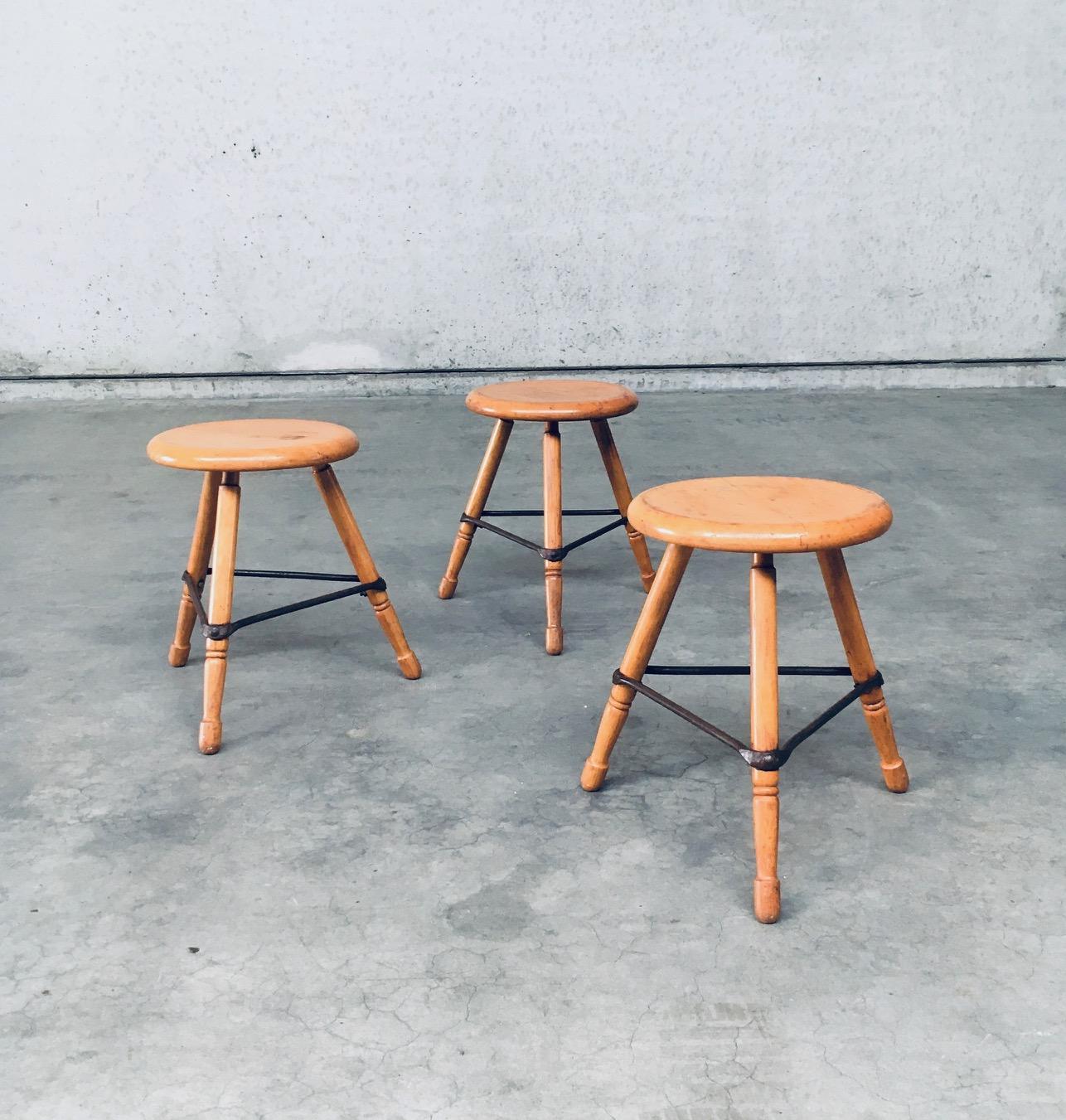 Vintage Midcentury Industrial Design Low Tripod Stool set of 3. Made in Belgium, 1950's period. Marked D.L.O. on the bottom of one stool. Solid beech wood construction with iron border strenghtening strip. The legs are nicely turned and the seats
