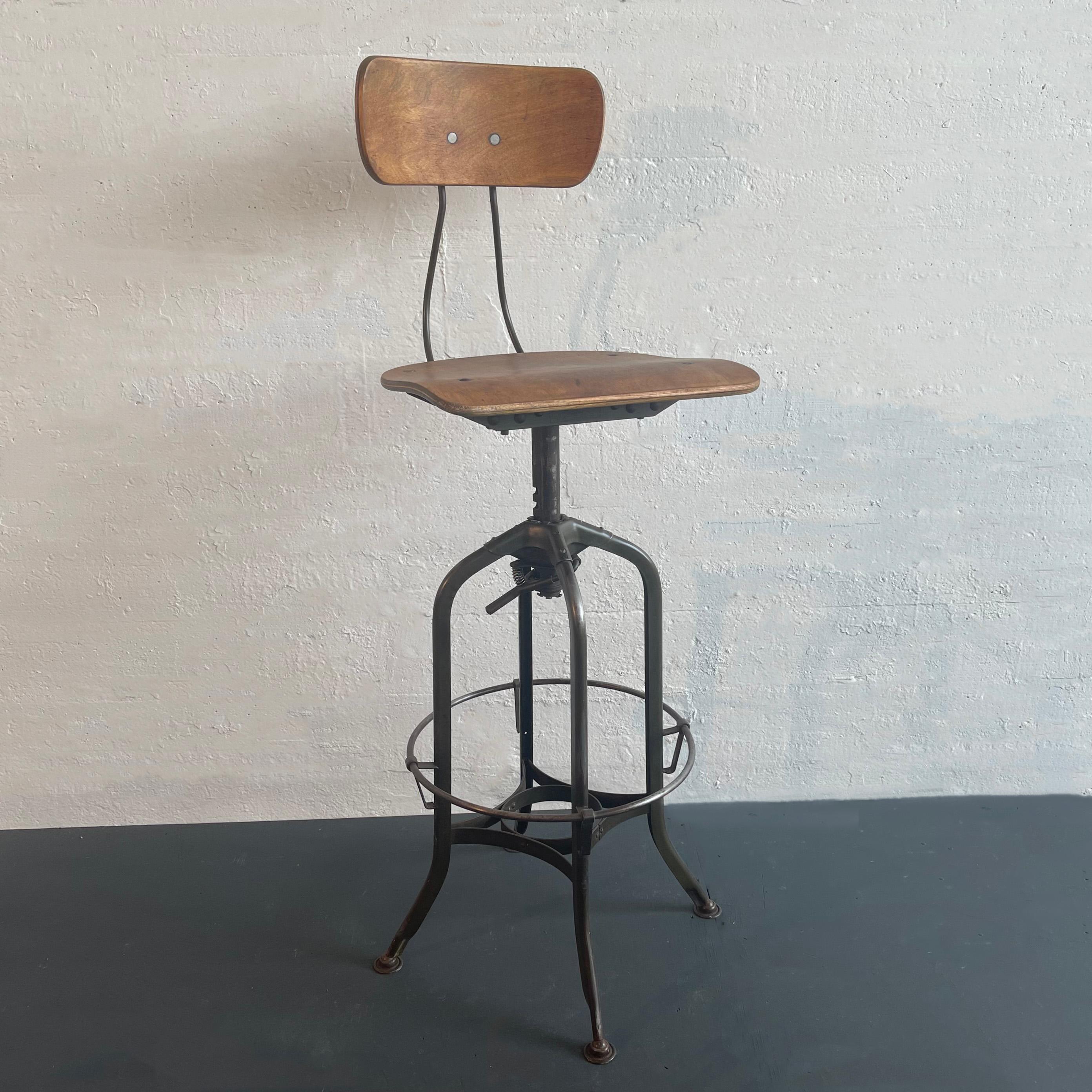 Iconic, vintage, industrial drafting stool by Toledo Metal Furniture Co. circa 1940's features a refinished bent ply maple, potato chip seat and back that swivels on a painted steel, star base with a 16.5 inch diameter foot rest at 12.5 inches