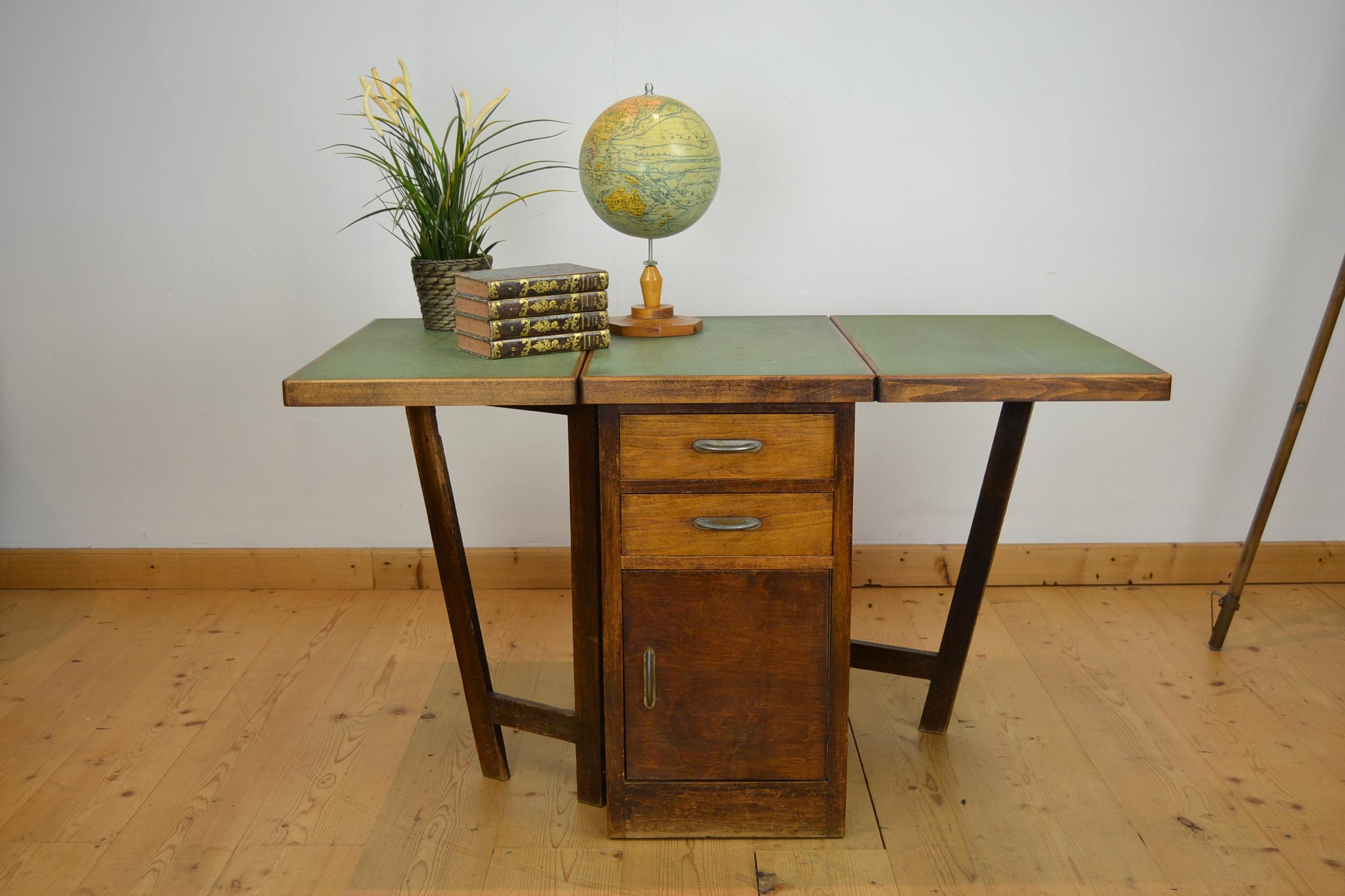 Great looking industrial drop leaf table. 
This wooden table has 2 drop leafs and storage space under on both sides: 
on 1 side 2 drawers and a door, on the other side a door. 
The top of the table is made of green speckled linoleum -
