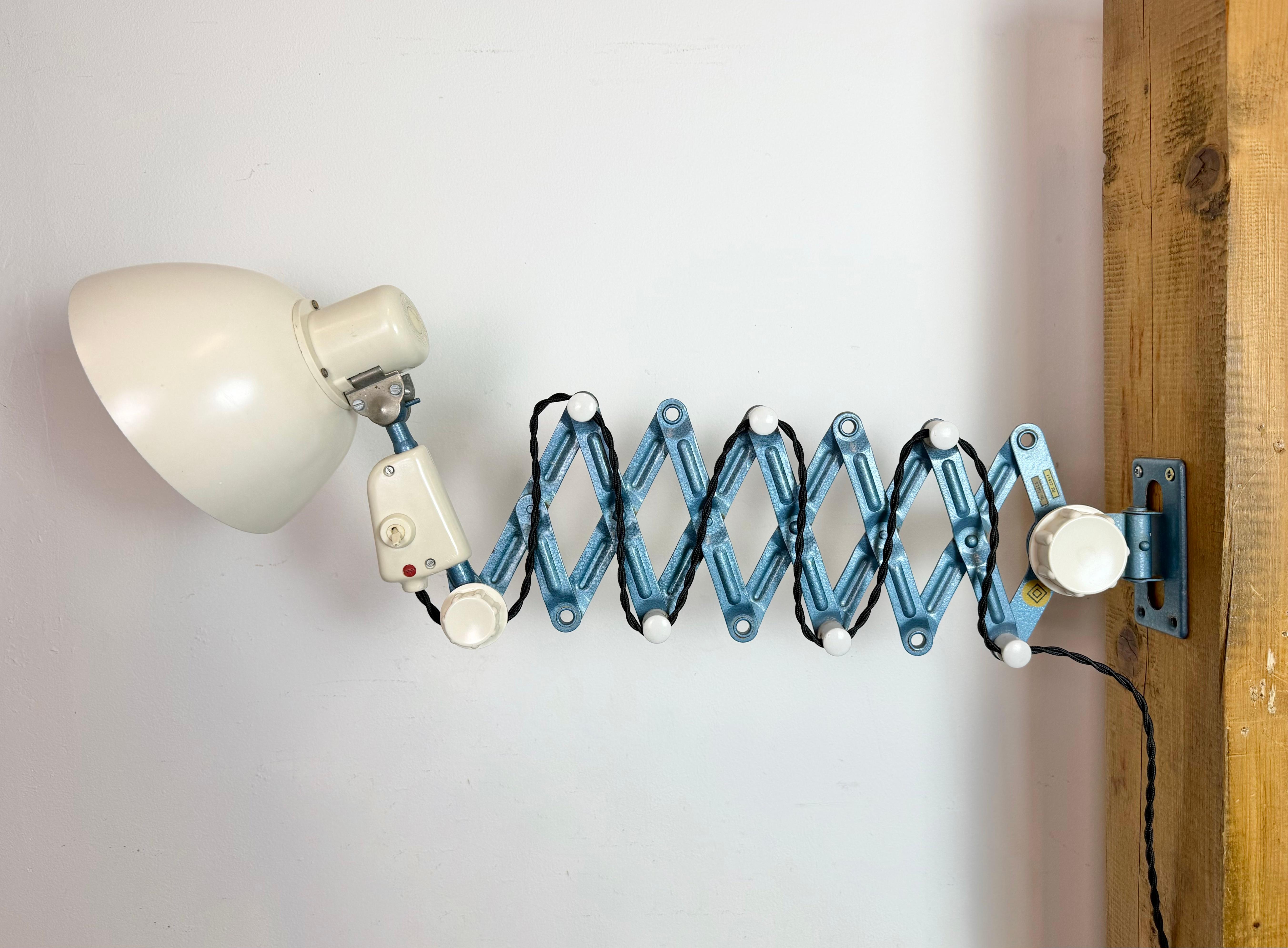 Questa lampada a forbice industriale vintage è stata prodotta da Reif Dresden, nell'ex Germania dell'Est, negli anni '50. La lampada ha un paralume in bachelite bianca (beige). Il braccio a forbice in ferro blu è estensibile e può essere girato